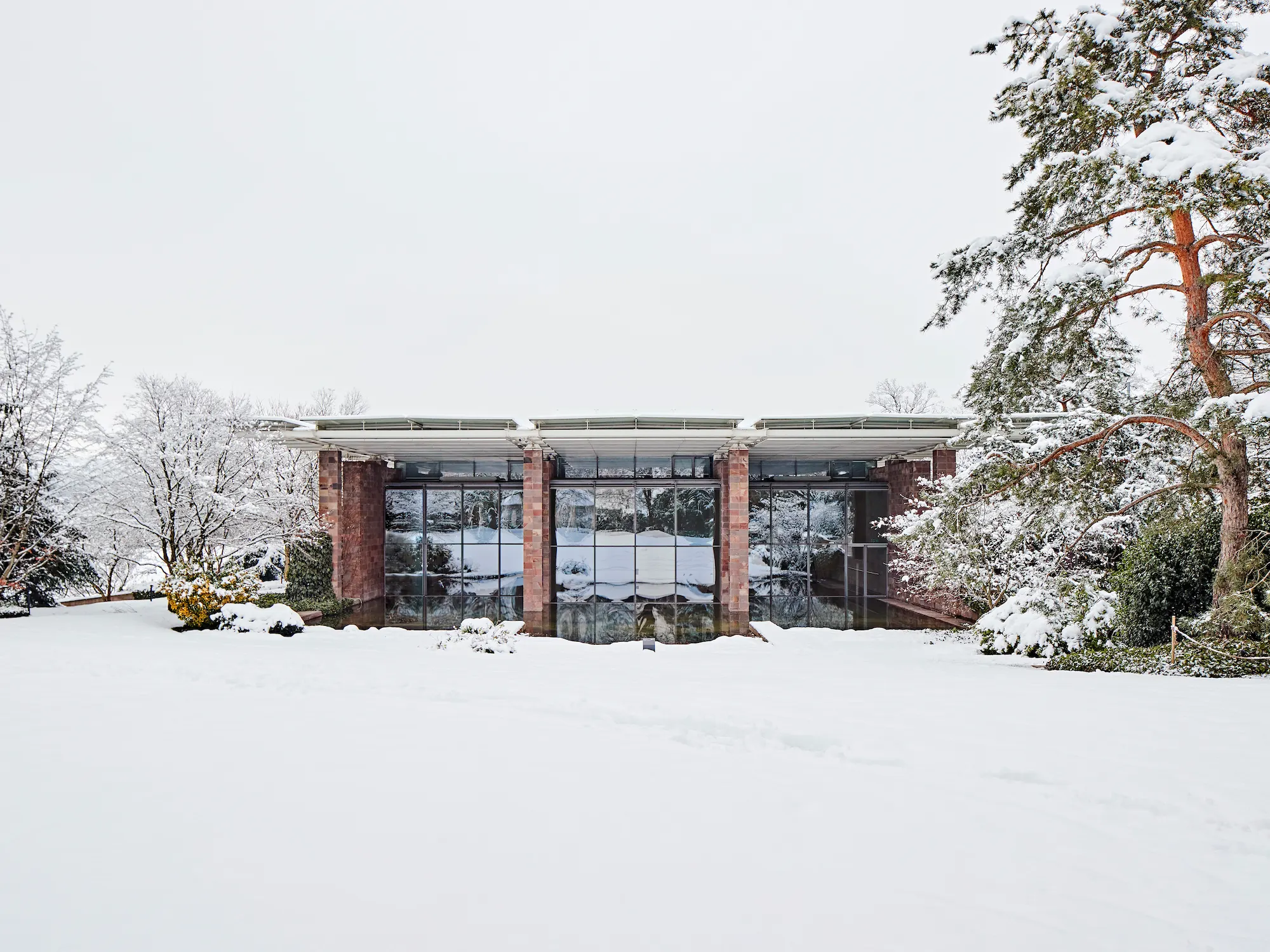 Fondation Beyeler museum in winter snow designed by Renzo Piano with glass pavilion architecture in Berower Park Basel Switzerland