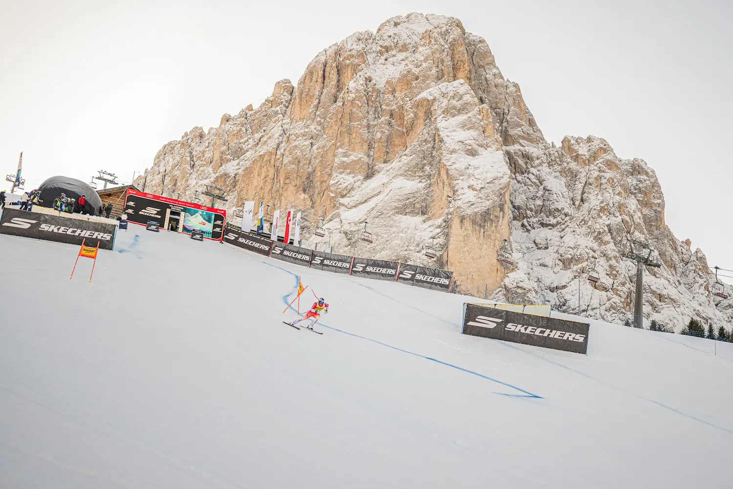 Downhill skier racing on legendary Saslong slope with dramatic Dolomite mountain backdrop at FIS World Cup Val Gardena South Tyrol Italy