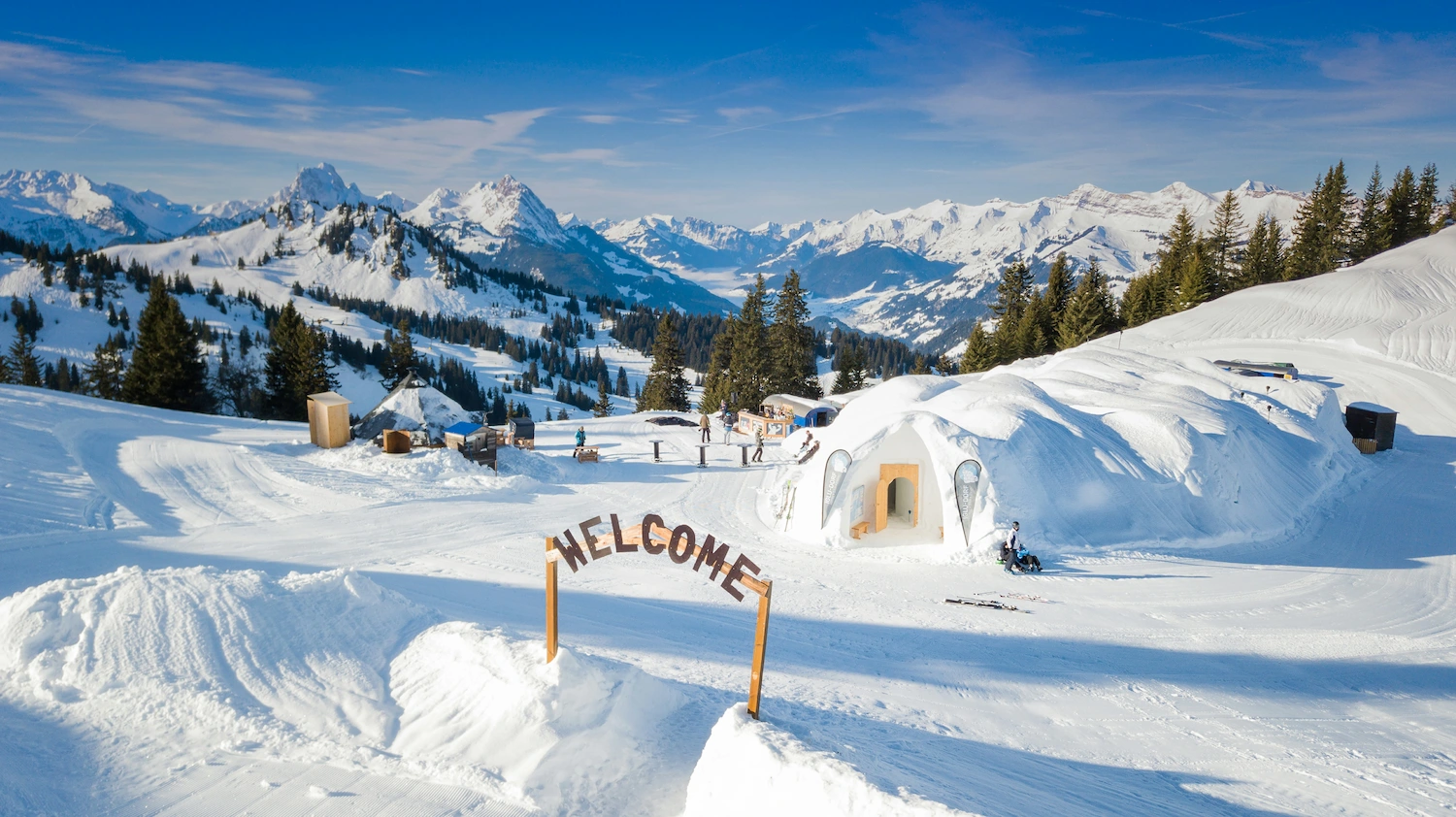 Igloo Dorf Gstaad ice hotel village with hand-carved snow igloos and welcome sign at 2000 meters in Bernese Oberland Swiss Alps mountains
