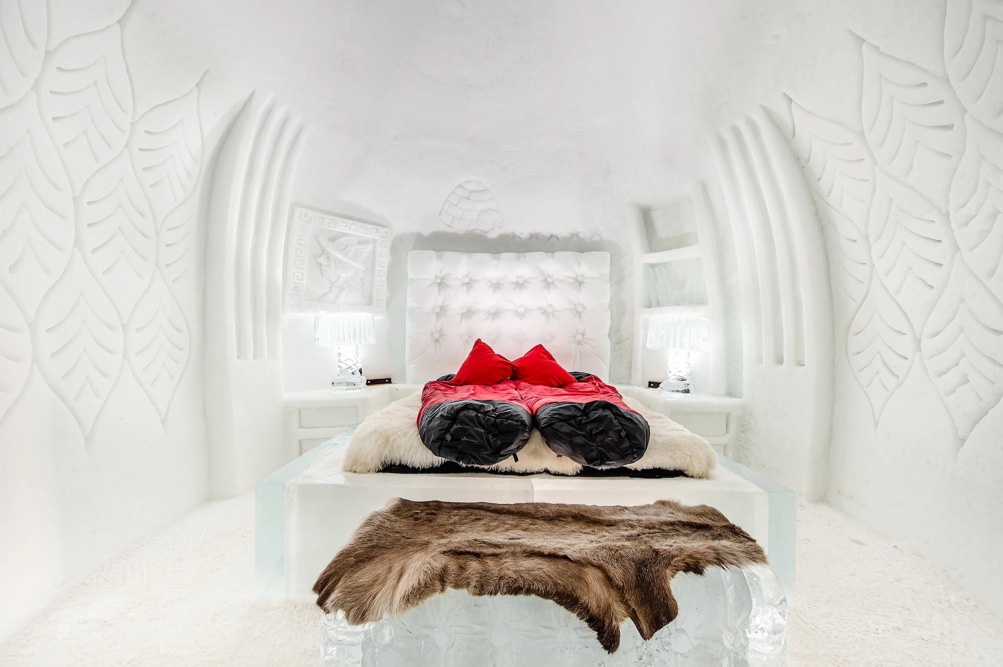 Luxury ice suite bedroom at Igloo Dorf Gstaad with carved ice bed reindeer fur throws and sculptural snow walls for romantic alpine getaway