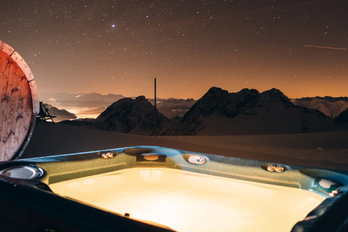 Luxury private hot tub at Igloo Dorf Gstaad with starry night sky and dramatic Bernese Alps mountain panorama at 2000 meters elevation