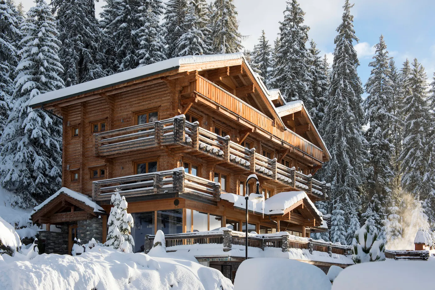 The Lodge Verbier Virgin Limited Edition luxury alpine chalet with traditional wooden architecture and snow-covered balconies in Swiss Alps forest