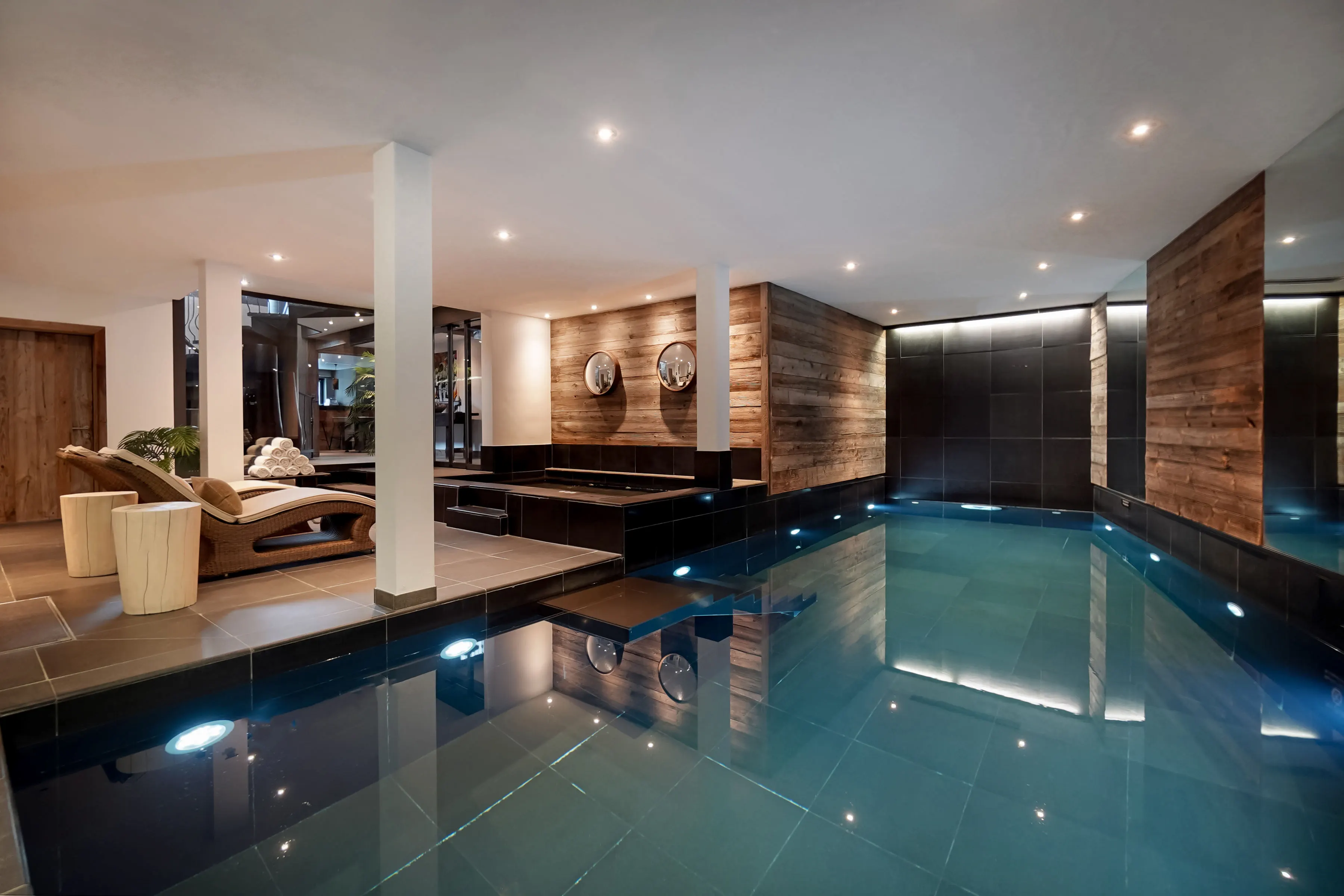 Luxury 9-meter heated indoor swimming pool with contemporary wood design and ambient lighting at The Lodge Verbier spa facilities