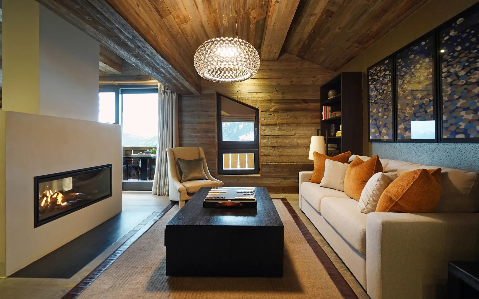 Master suite private lounge at The Lodge Verbier with contemporary fireplace orange accent cushions and alpine balcony views in Fiona Barratt design
