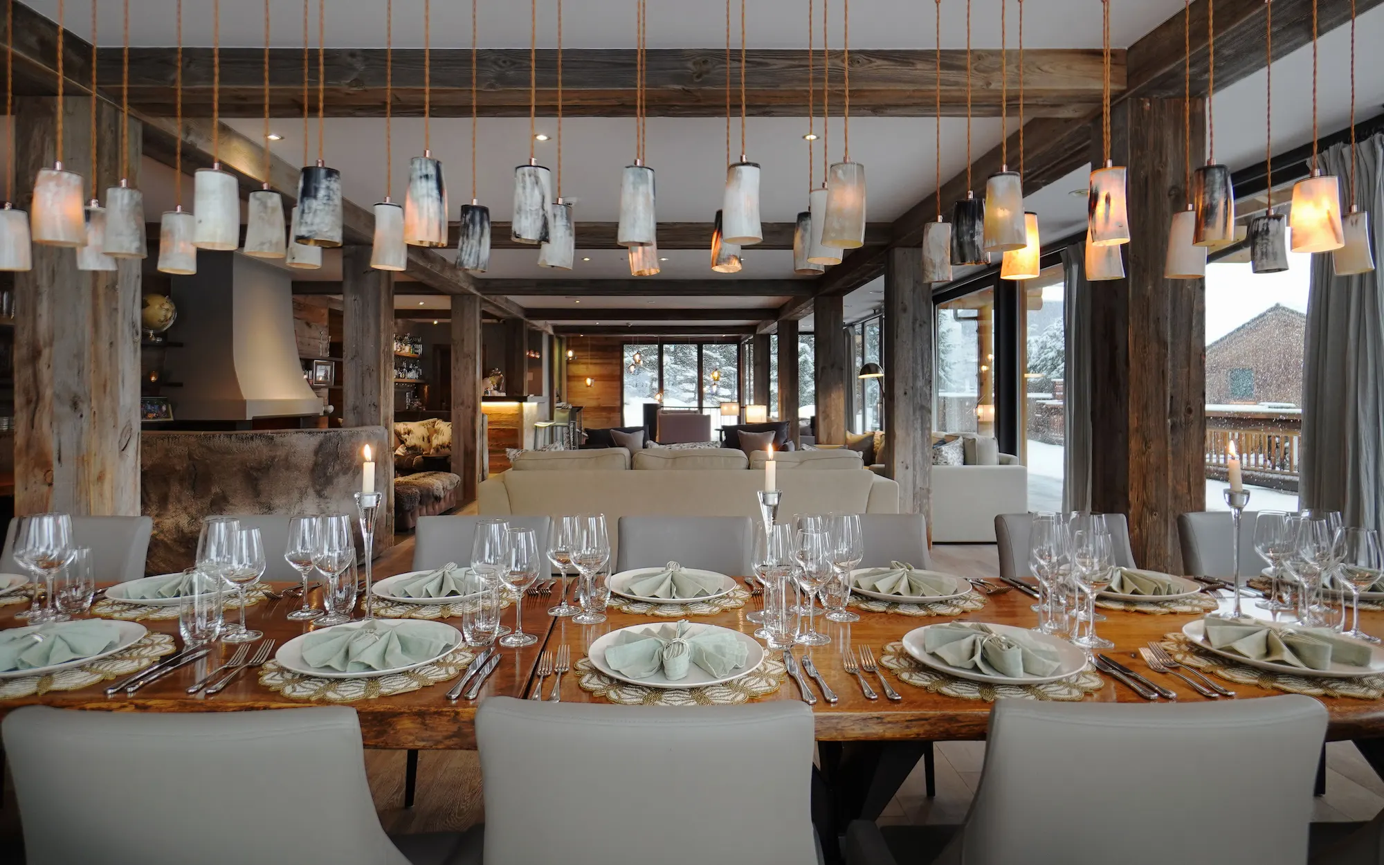 Elegant formal dining room at The Lodge Verbier with live-edge wood table handcrafted pendant lights and open-plan design with mountain views
