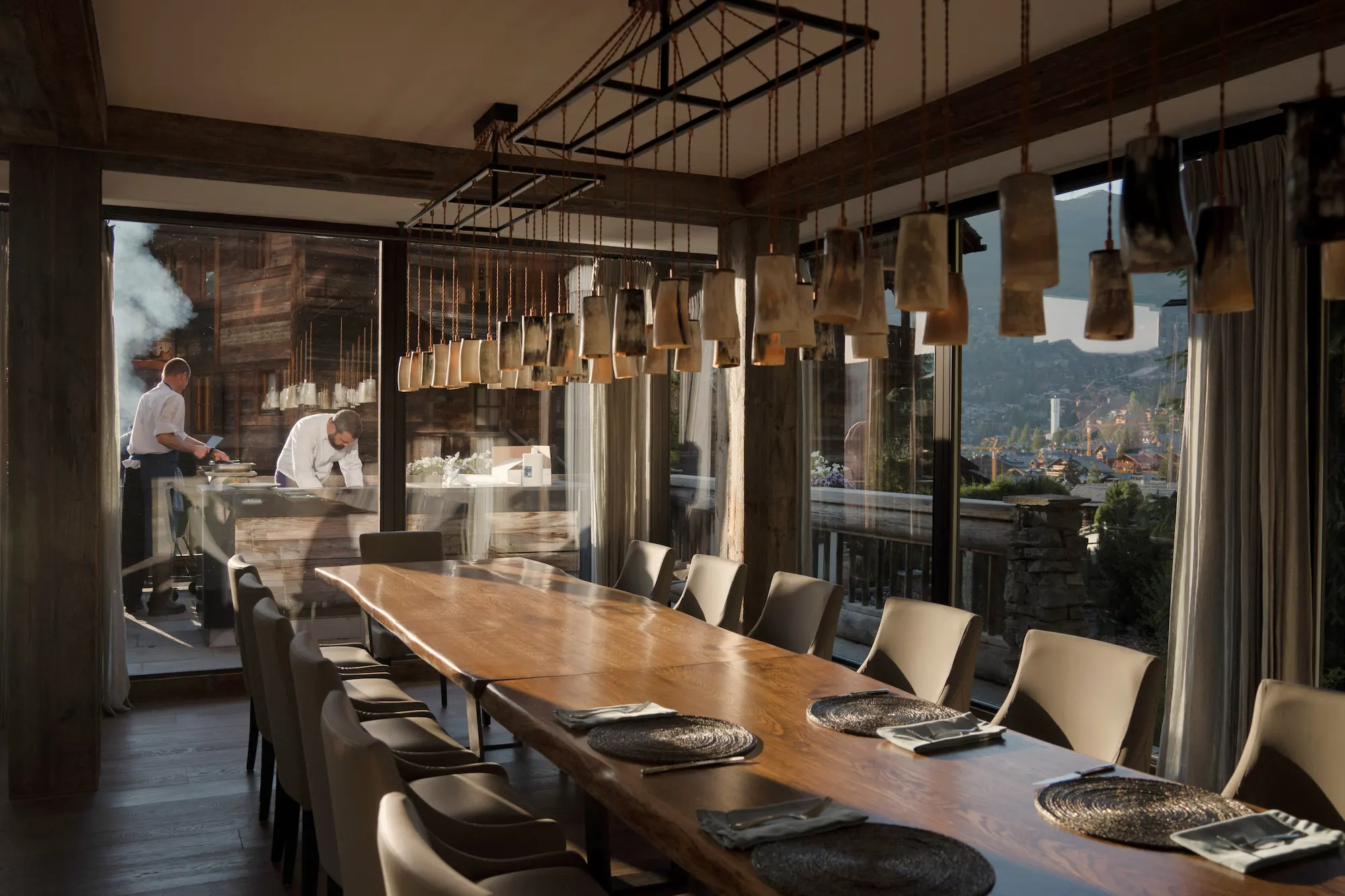 Open chef's kitchen with Michelin-trained culinary team preparing gourmet meals at The Lodge Verbier dining room with Verbier valley views