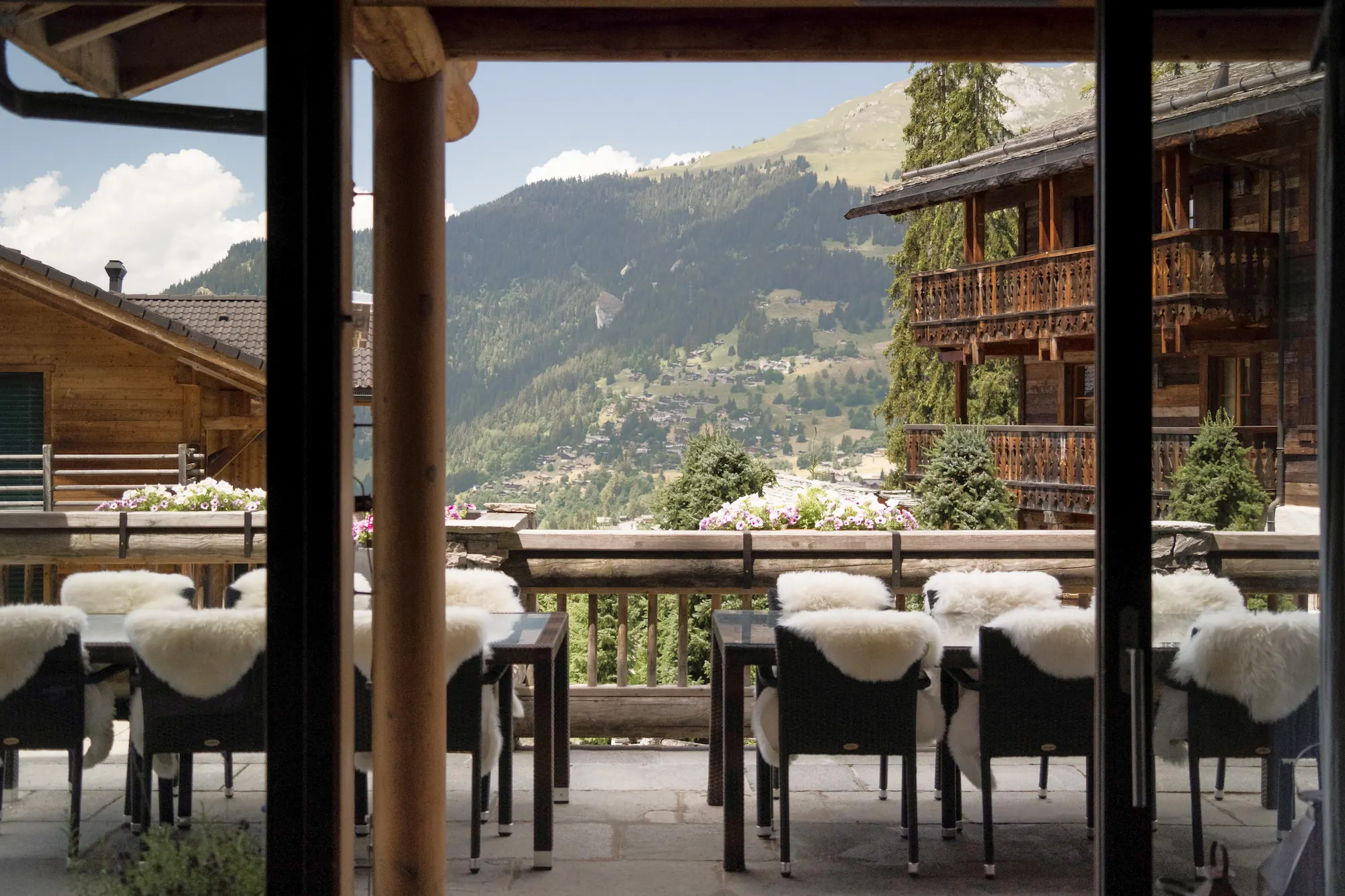 Outdoor terrace dining with sheepskin-draped chairs and panoramic Verbier village views at The Lodge Virgin Limited Edition