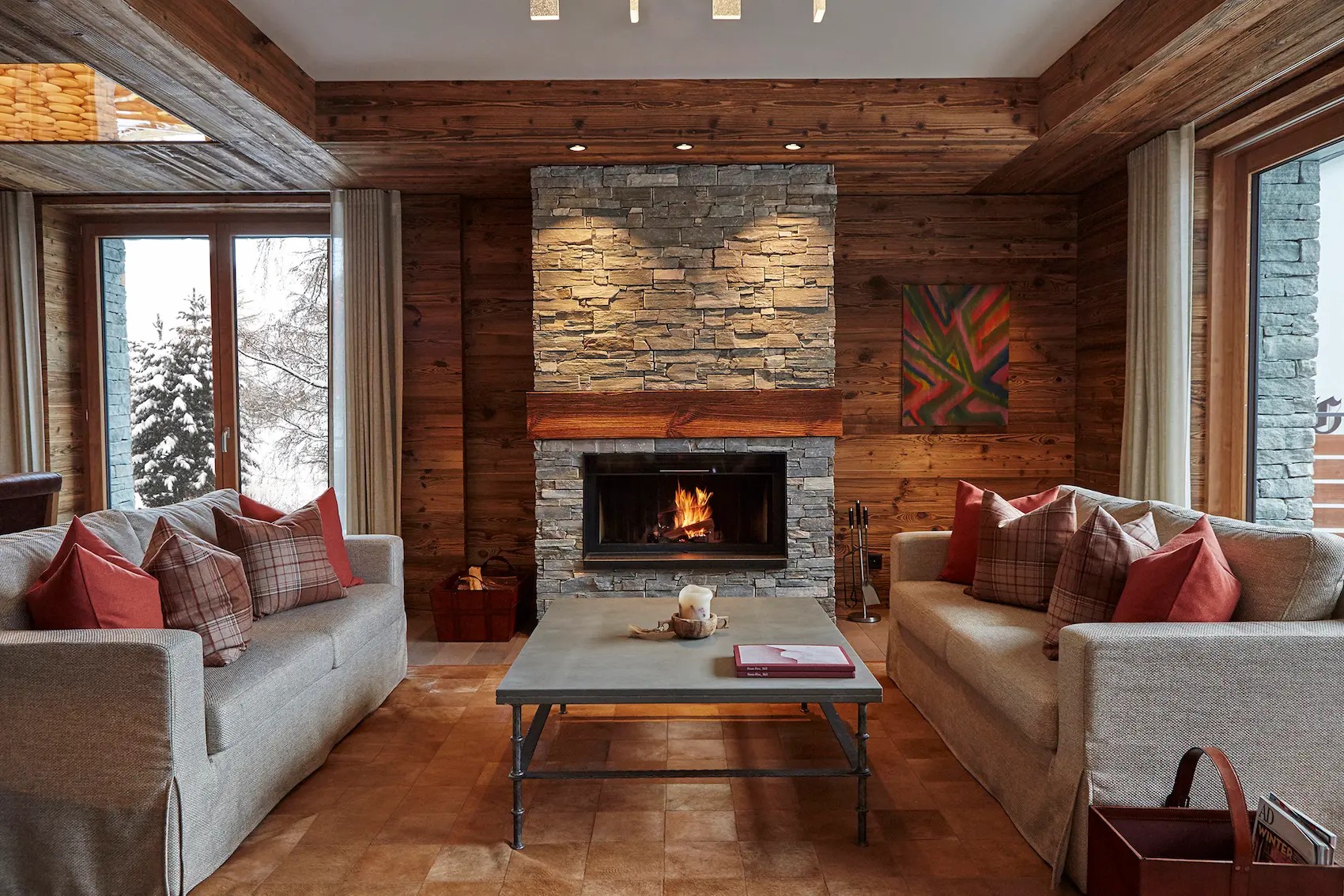 Cozy lobby lounge at The Capra hotel featuring stone fireplace alpine pine paneling and contemporary furnishings with snowy mountain views in Saas-Fee