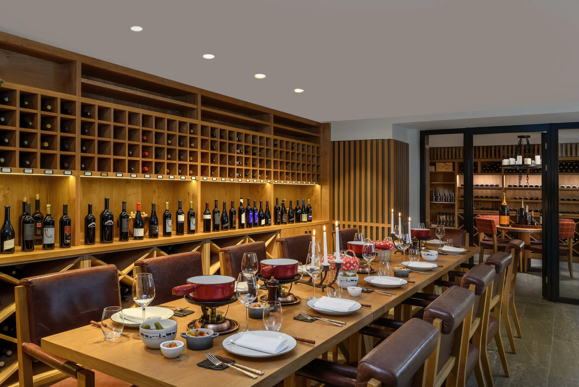 Private wine cellar dining room at The Capra with extensive wine collection wooden storage and traditional Swiss fondue service in Saas-Fee
