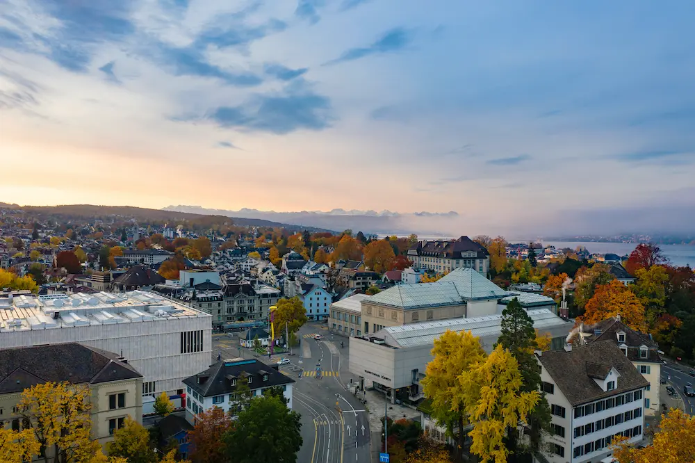 Aerial autumn view of Kunsthaus Zürich showing David Chipperfield extension pale stone pavilion and historic museum buildings overlooking Lake Zurich with fall foliage