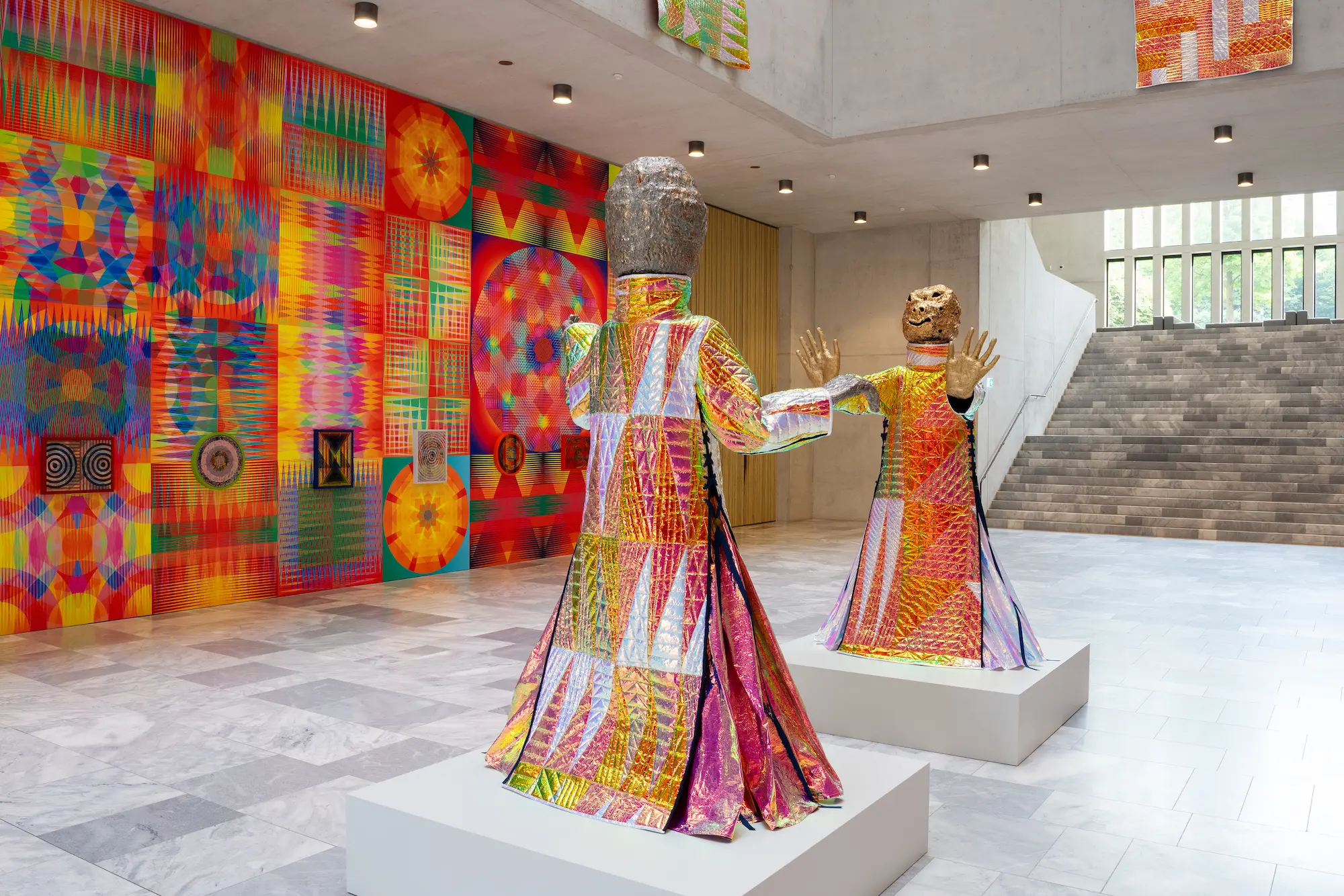 Jeffrey Gibson boshullichi inlᴜchi installation at Kunsthaus Zürich Haefner Foyer featuring colorful beaded dresses textiles and geometric patterns in Chipperfield extension