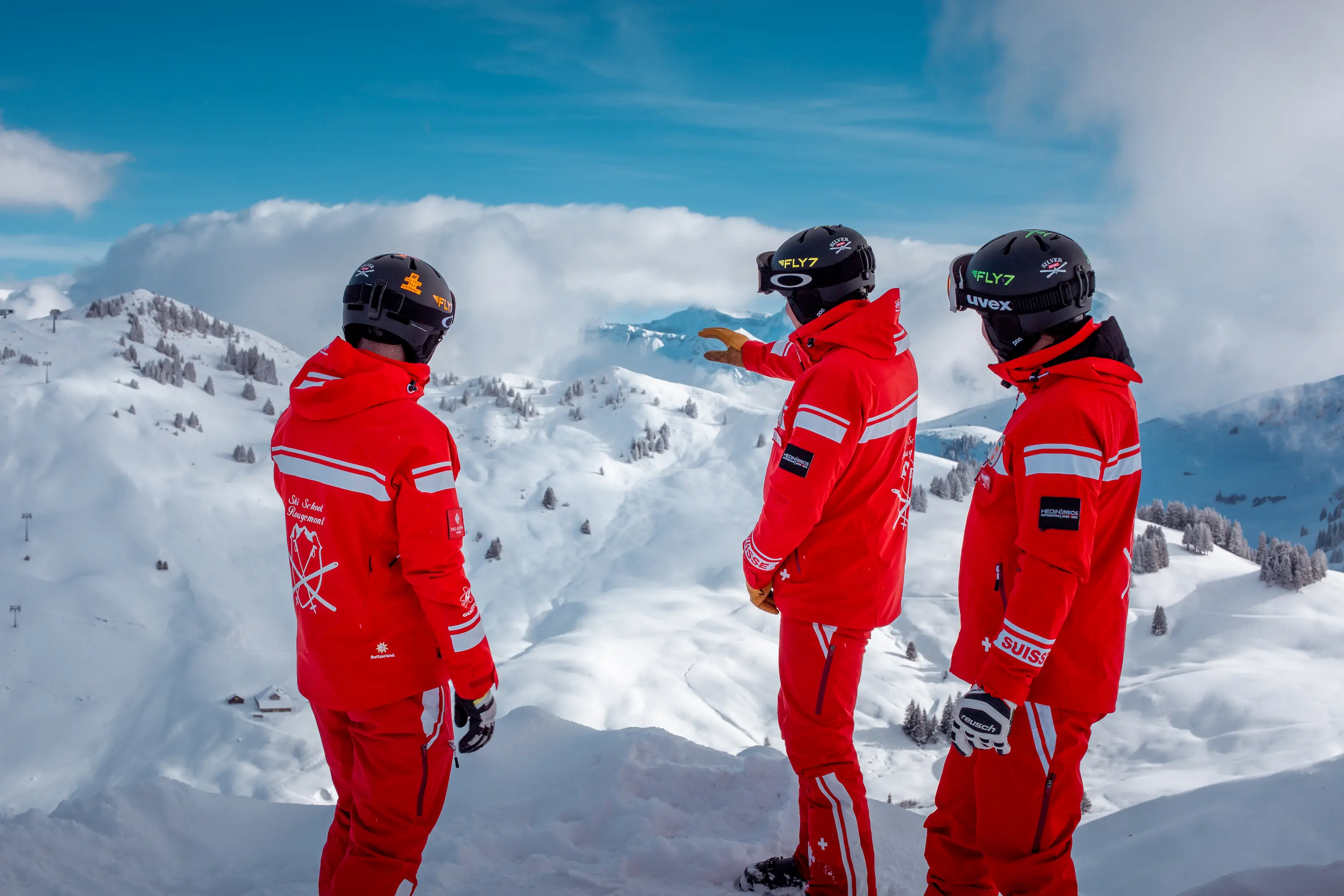 Ski School Rougemont multilingual instructors in signature red uniforms surveying Videmanette slopes and 57km interconnected pistes in Gstaad region Bernese Oberland