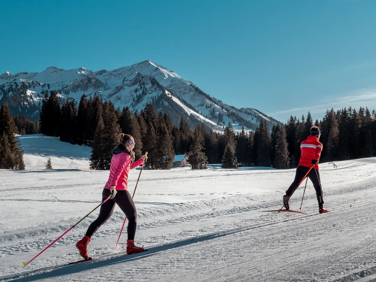 Professional ski instructor at Ski School Rougemont demonstrating expert technique on powder slopes with dramatic Pays d'Enhaut cliffs and larch forests near Gstaad