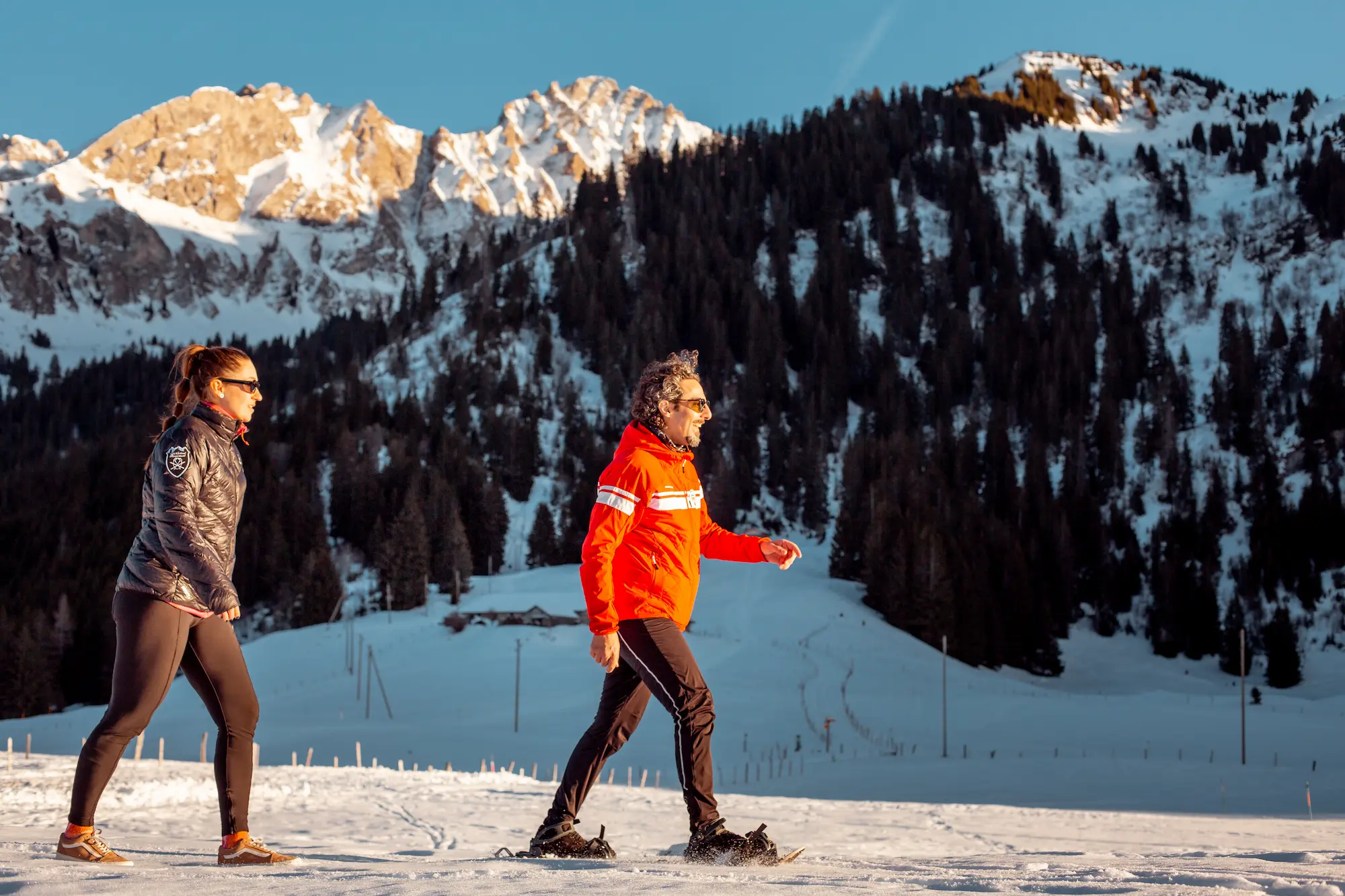 Private snowshoe trek led by Ski School Rougemont instructor through fir-scented forest at golden hour with dramatic Bernese Oberland peaks backdrop near Gstaad