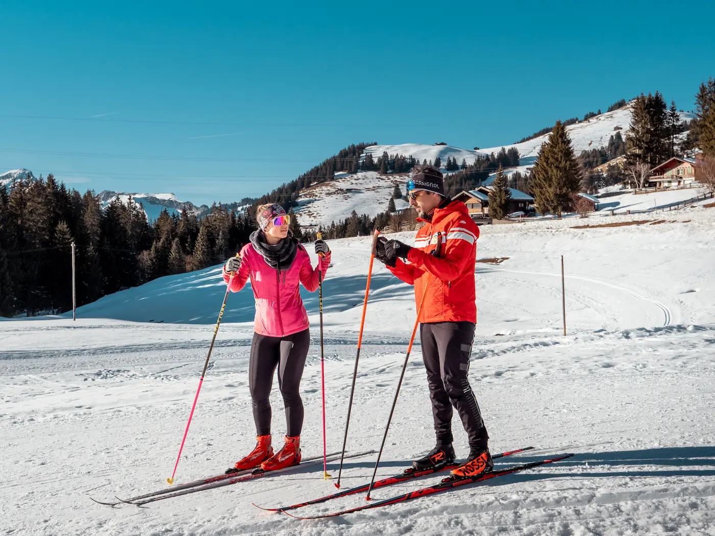 Cross-country skiing instruction at Ski School Rougemont with weathered flower-adorned chalets in authentic Pays d'Enhaut valley traditional Swiss village setting