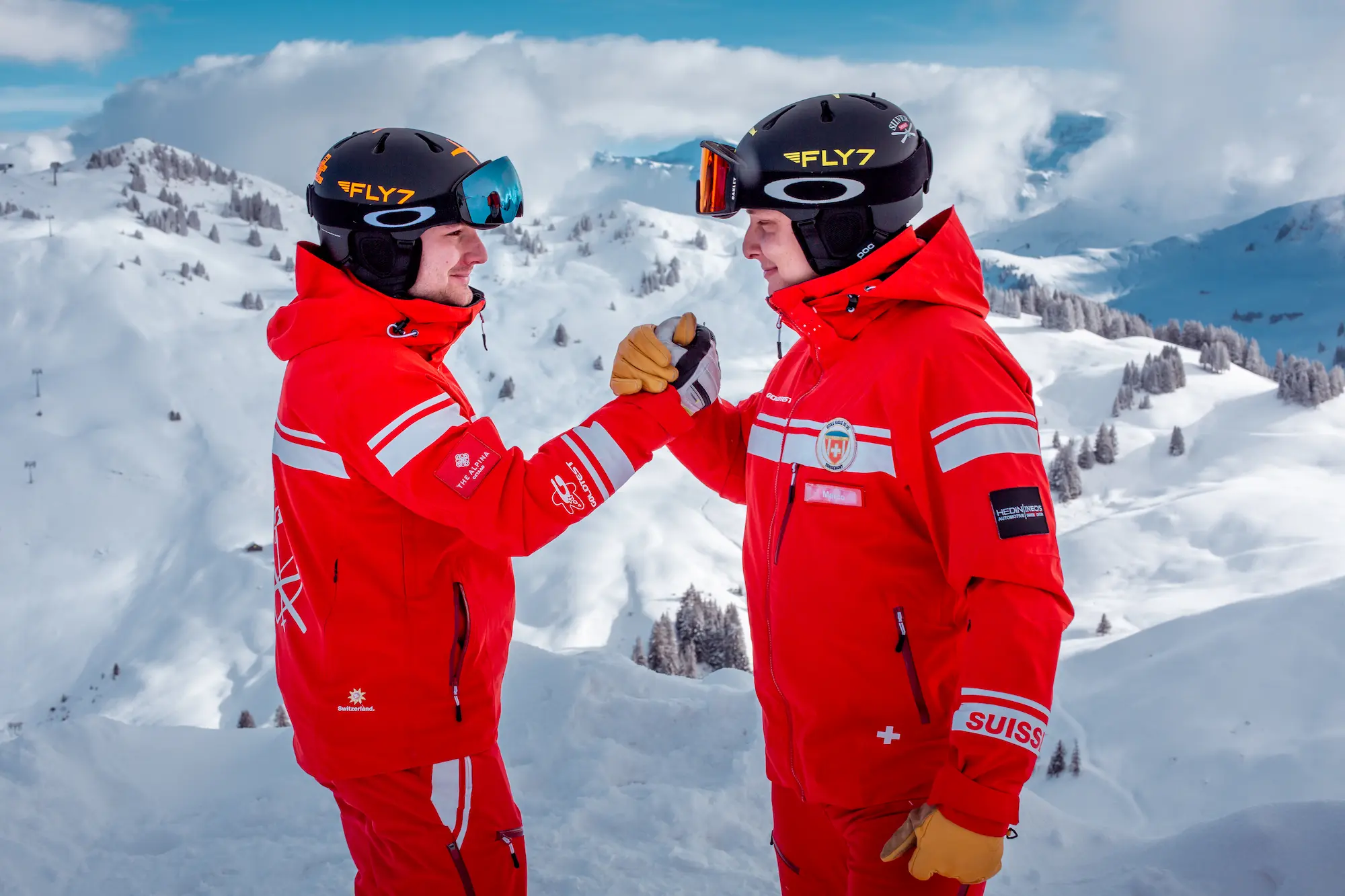 Ski School Rougemont professional instructors celebrating on mountain summit with panoramic views of Pays d'Enhaut valley and Bernese Oberland peaks near Gstaad