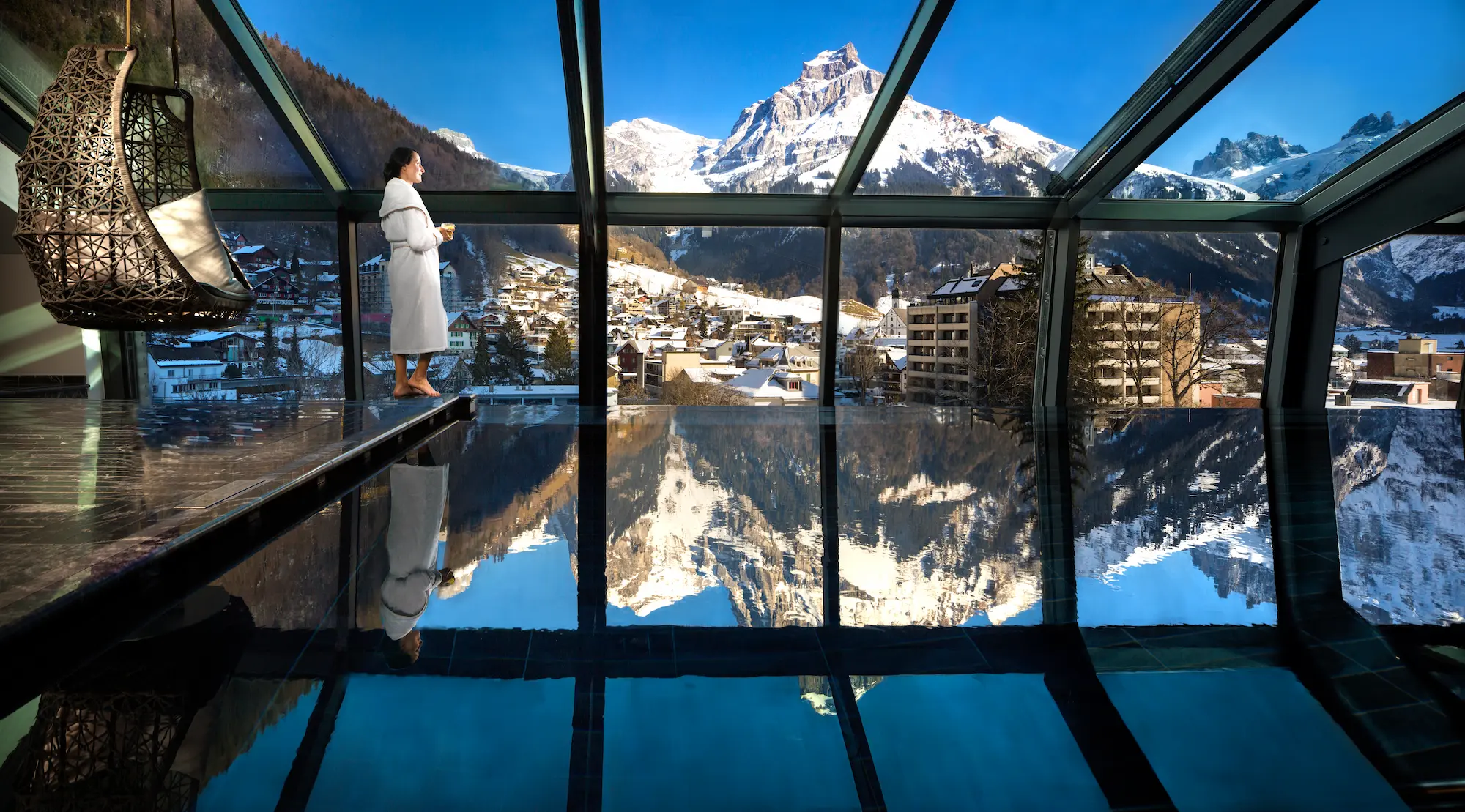 Kempinski Palace Engelberg 15-meter rooftop infinity pool with floor-to-ceiling glass panoramic Mount Titlis views and Engelberg valley reflecting dramatic Swiss Alps winter landscape