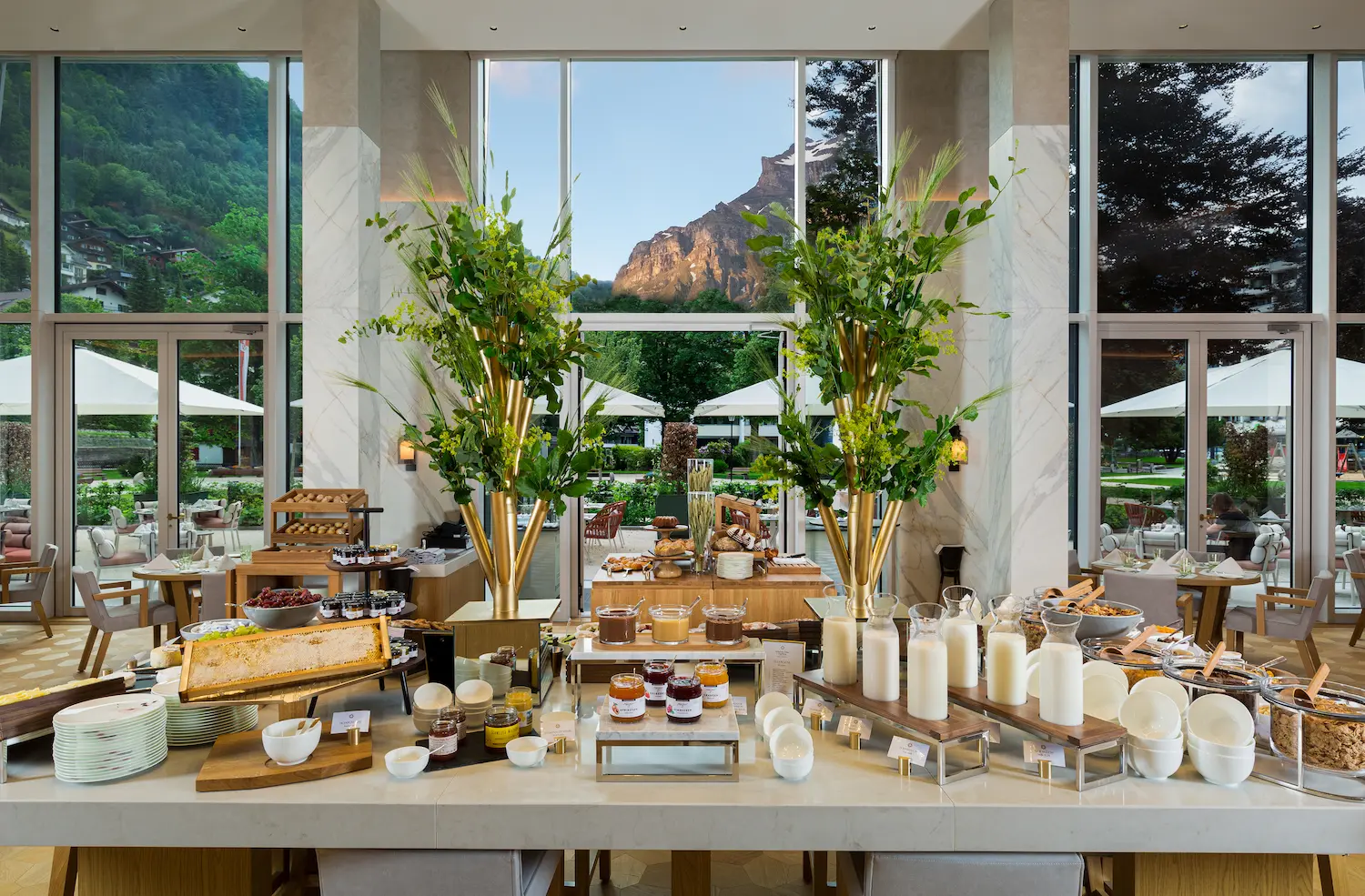Cattani Restaurant breakfast buffet at Kempinski Palace Engelberg with marble-clad walls soaring windows framing Mount Titlis and seasonal Swiss produce by Chef Michéle Müller