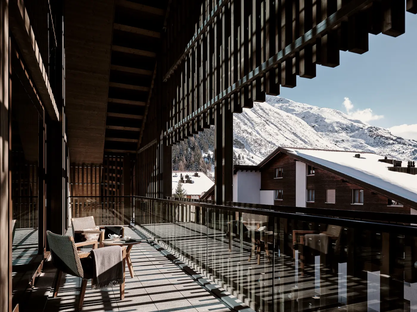 Luxury Furka Suite private terrace at The Chedi Andermatt with designer outdoor furniture, fur throws, glass balustrade, and panoramic views of snow-covered Ursern Valley and Swiss Alps