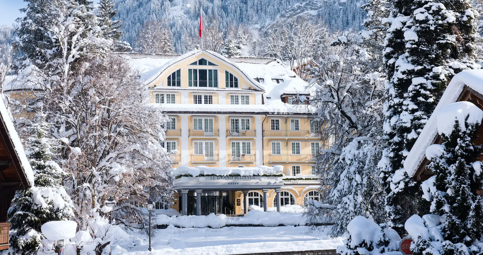 Le Grand Bellevue luxury 5-star hotel in winter with snow-covered facade and Swiss Alps mountains Gstaad Bernese Oberland