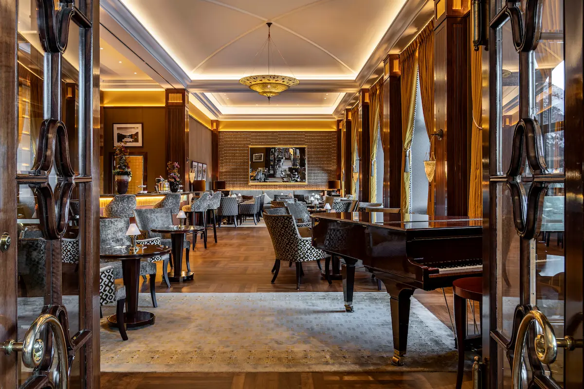 Refined games room at Suvretta House luxury hotel featuring antique billiards table, elegant arched architectural details, vintage furnishings, curated art collection, and classic European hotel design in St. Moritz