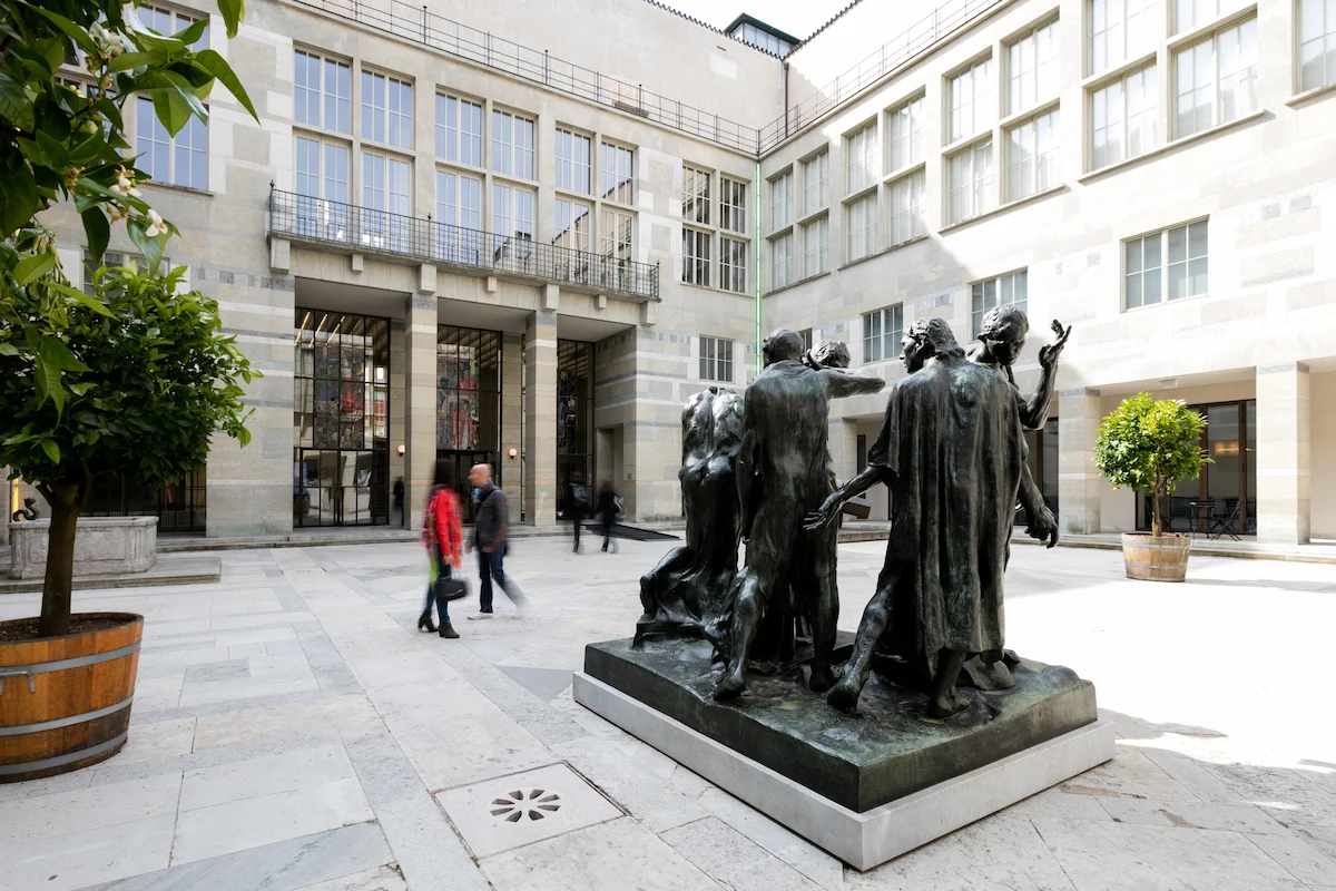 Bronze figurative sculpture group on white marble plinth in interior courtyard of Kunstmuseum Basel neoclassical building with limestone facade