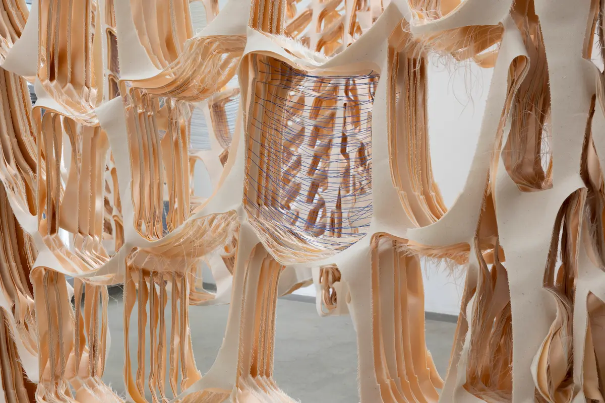 Close-up detail of Satin Overlap by Isabel Fletcher showing delicate peach and white satin ribbons interwoven with transparent organza creating ethereal three-dimensional textile sculpture