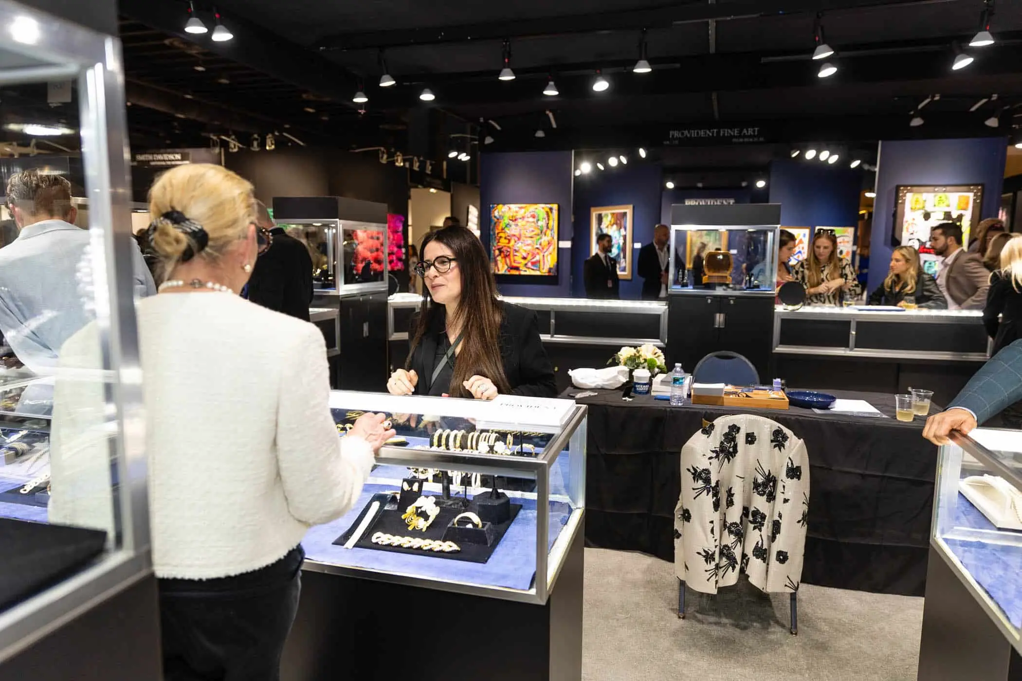 Sophisticated jewelry consultation at The Palm Beach Show 2026 featuring luxury jewelry dealer presenting estate pieces including pearl necklaces