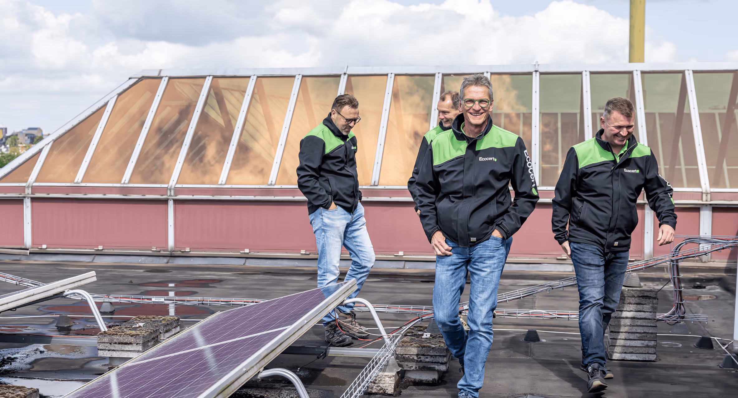 Vier Ecocert medewerker lopen op het dak met zonnepanelen van een utiliteit gebouw