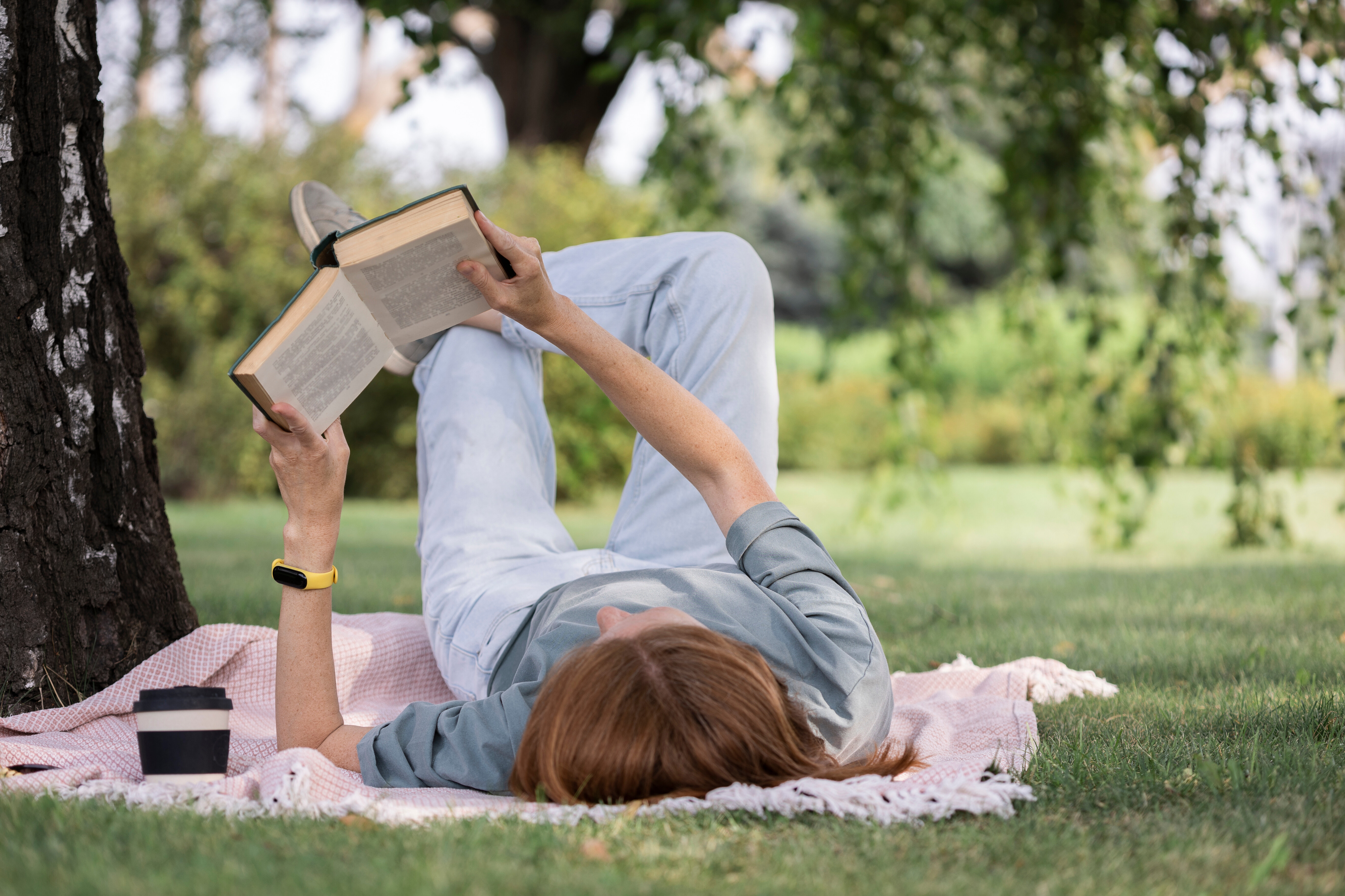 laying on grass reading book stock image