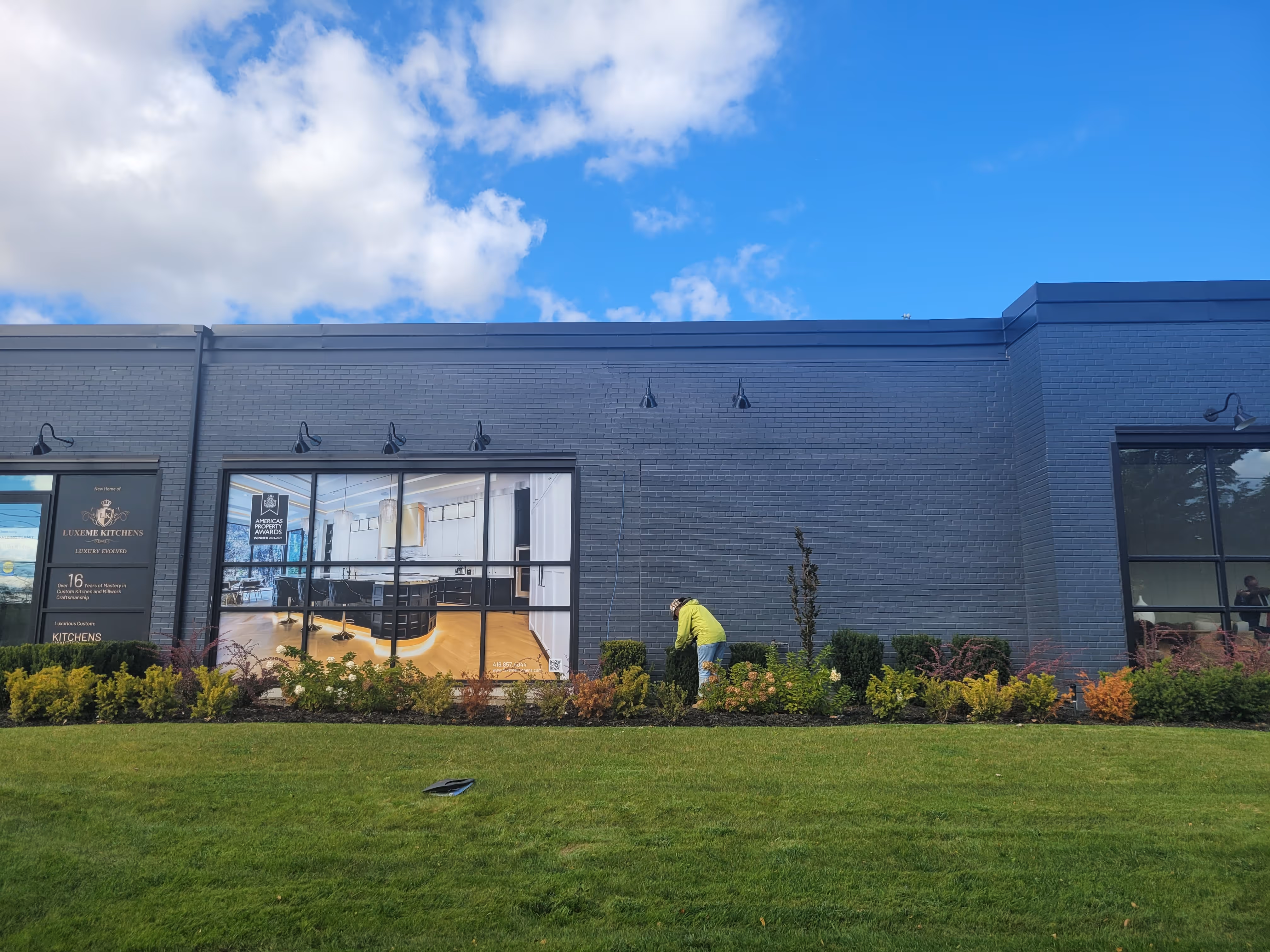 A vibrant green lawn stretches across the foreground, leading up to a well-defined garden bed that runs along the base of the building