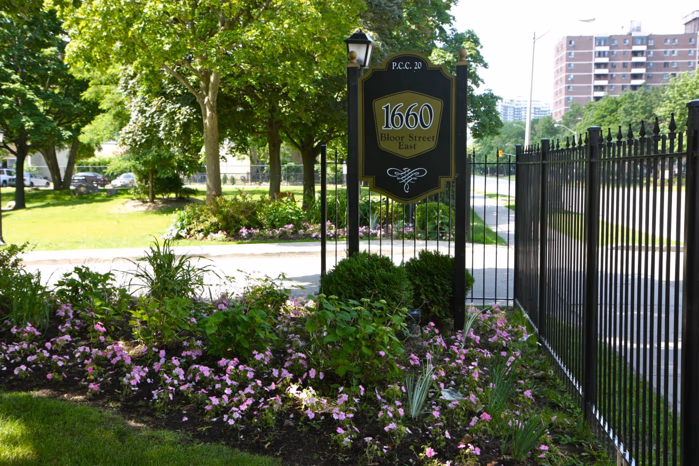 wrought iron fence and perennial garden beds showcases property sign