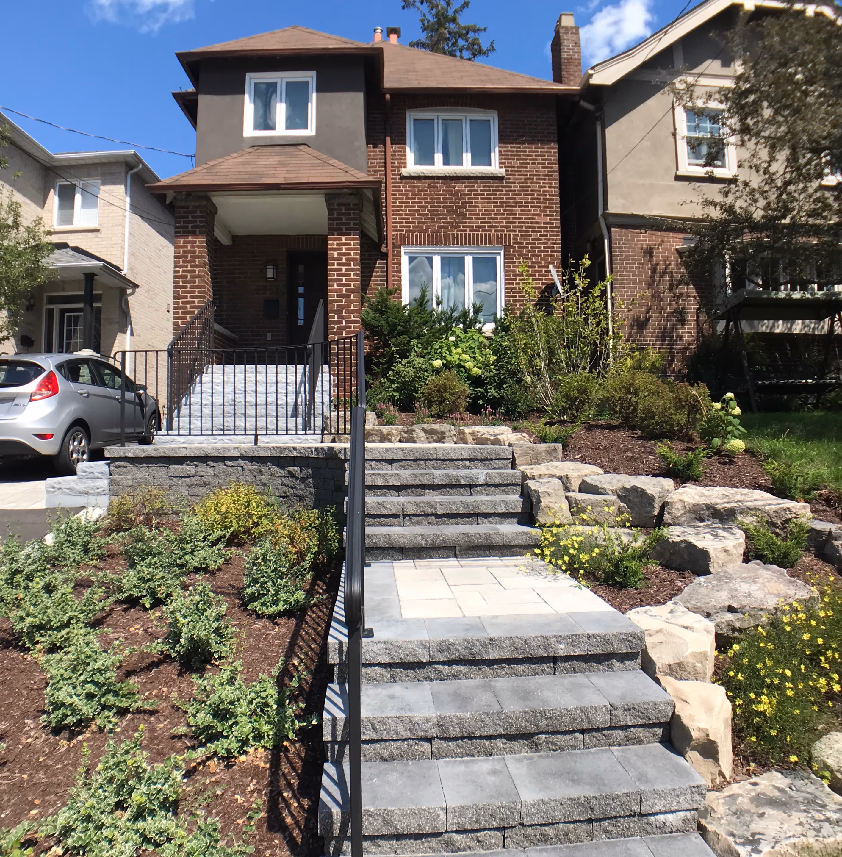 natural brown mulch perennial flower beds with natural stone stair case and black iron hand railing