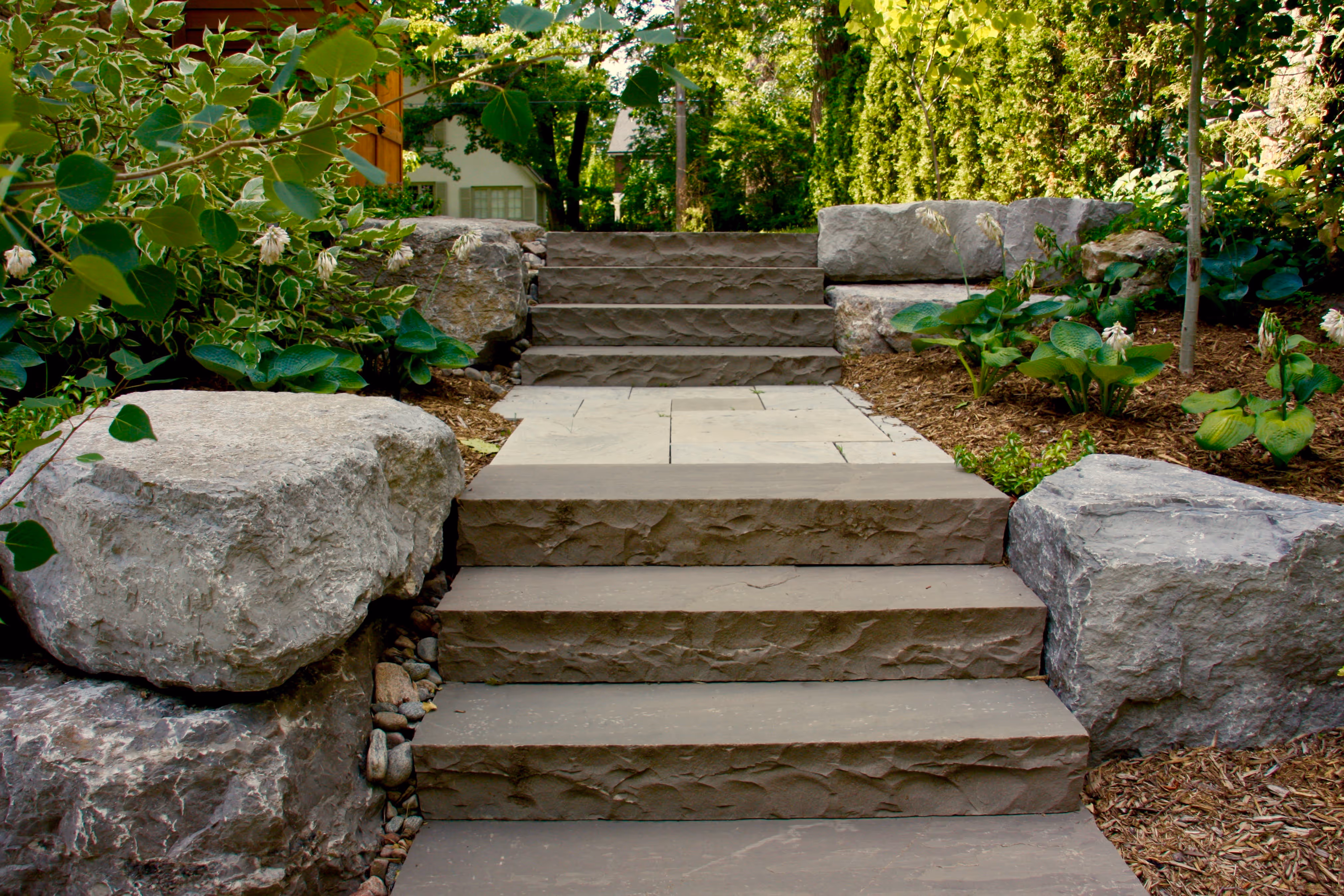 Natural stone rocks fill gardens beds of natural brown mulch
