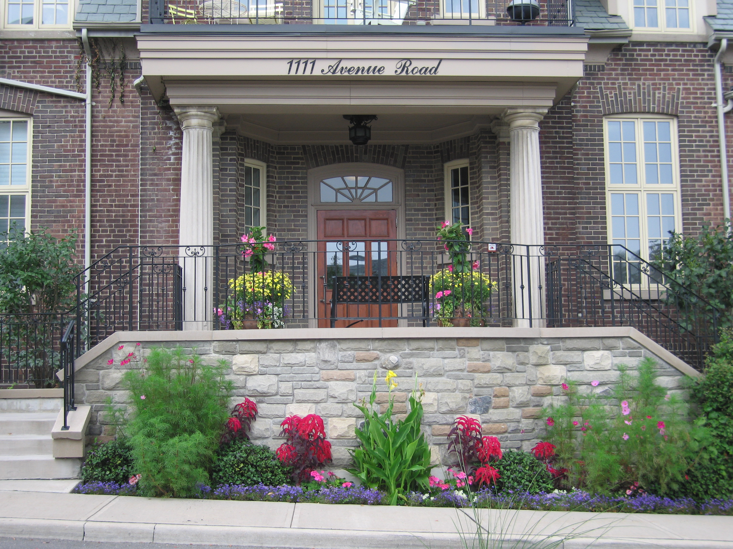 Town home with small garden beds out front and Urns at each door