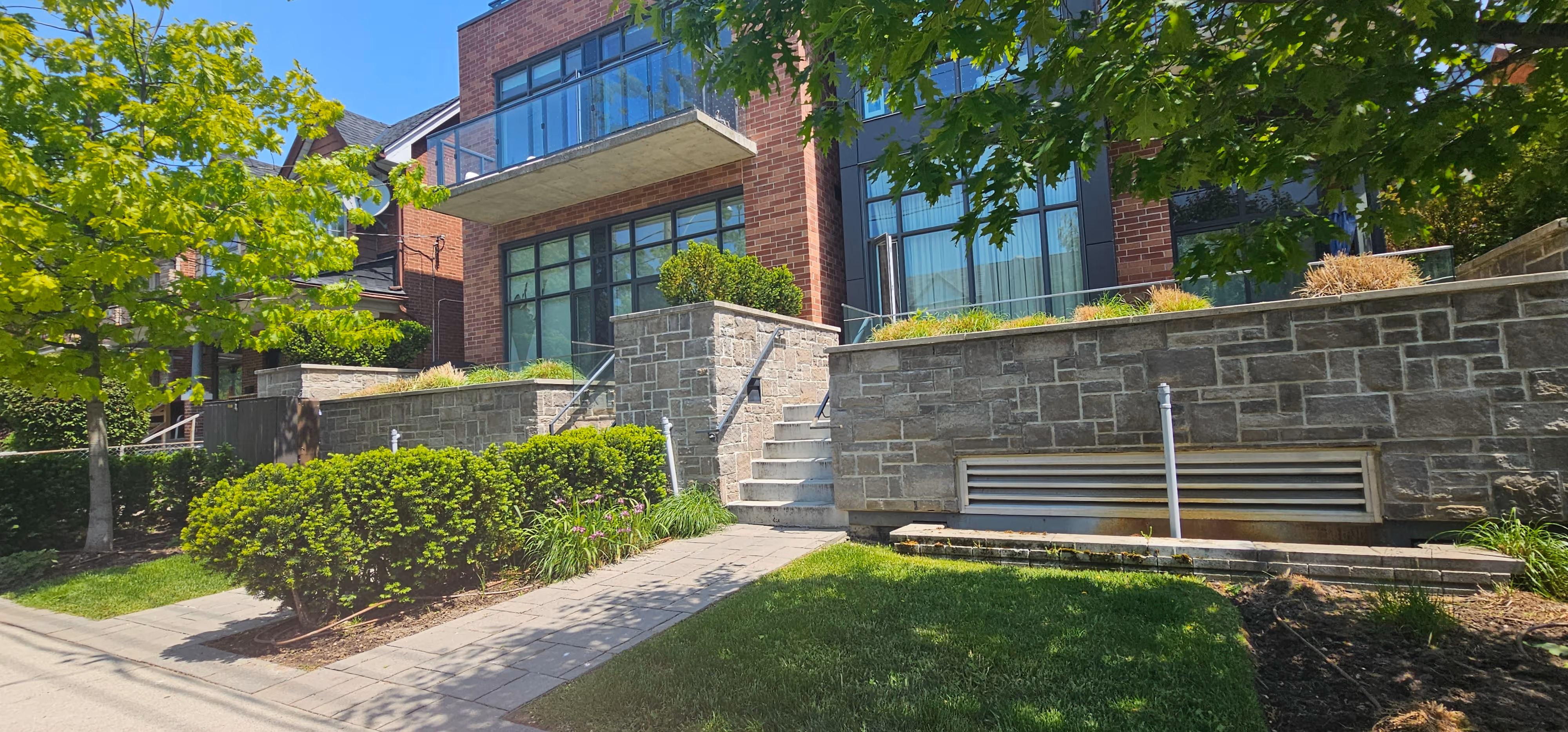 Outdoor entrances to multiple different units with yew hedges and trees