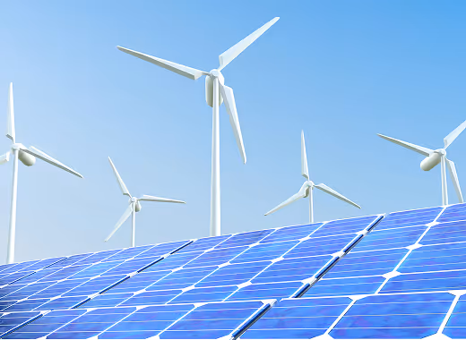 Solar panels in the foreground with wind turbines in the background under a clear blue sky.