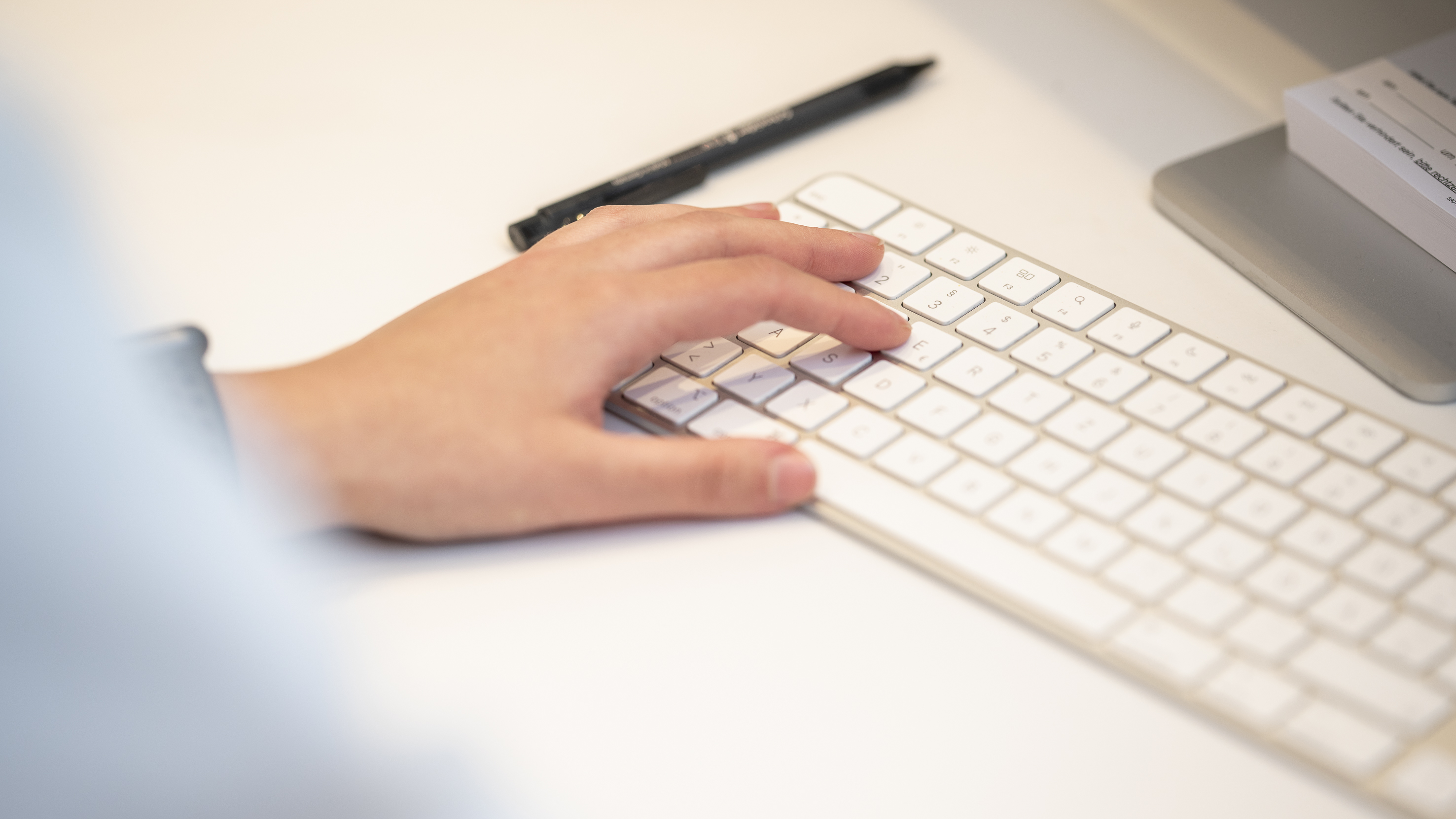 Nahaufnahme einer Hand, welche auf einer Apple Tastatur schreibt.