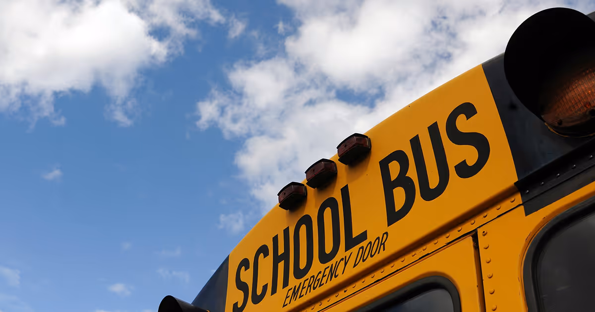The back of a school bus against a partially cloudy sky.