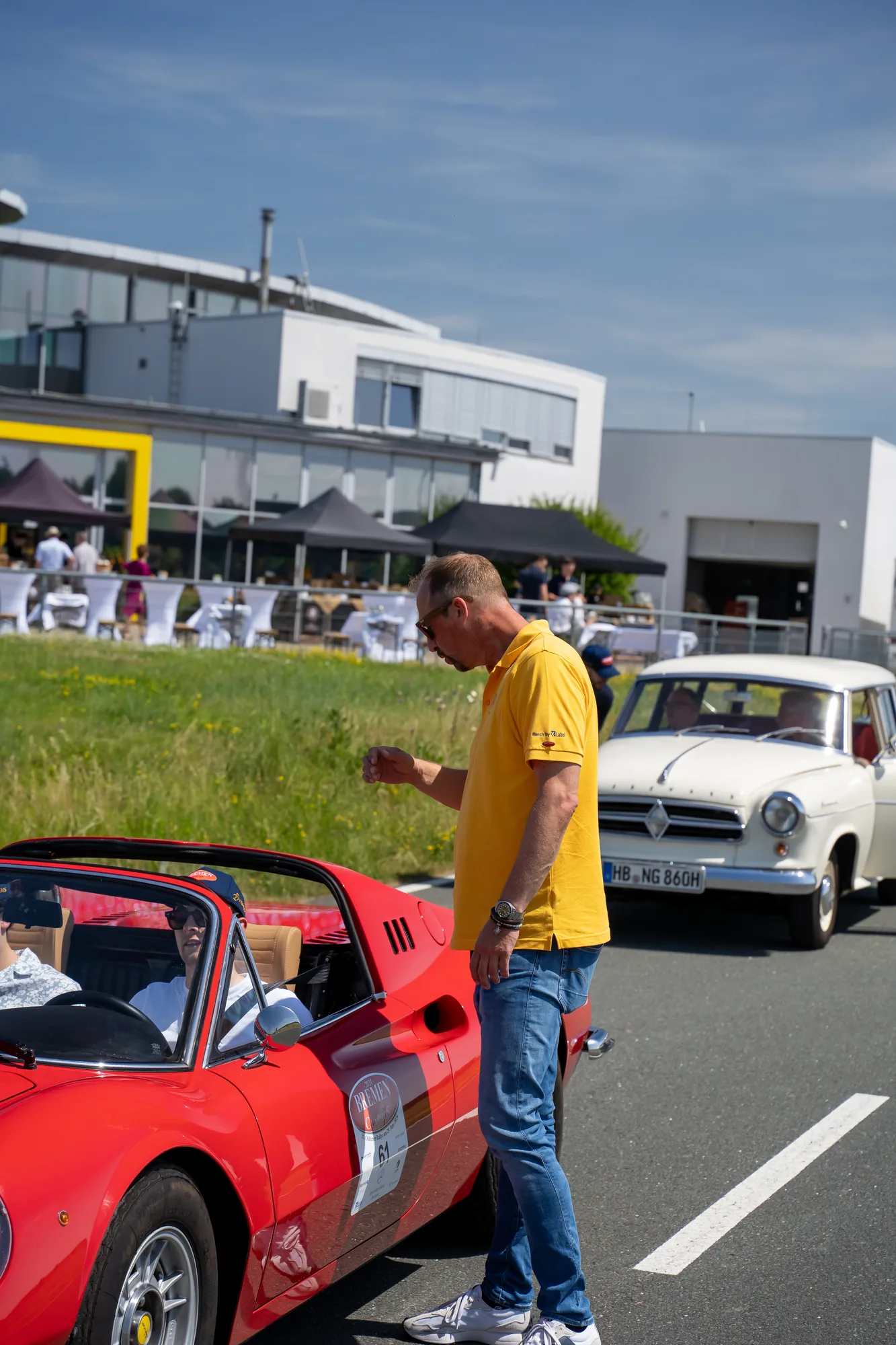 Teilnehmer neben einem roten Sportwagen bei den BOC 2024.