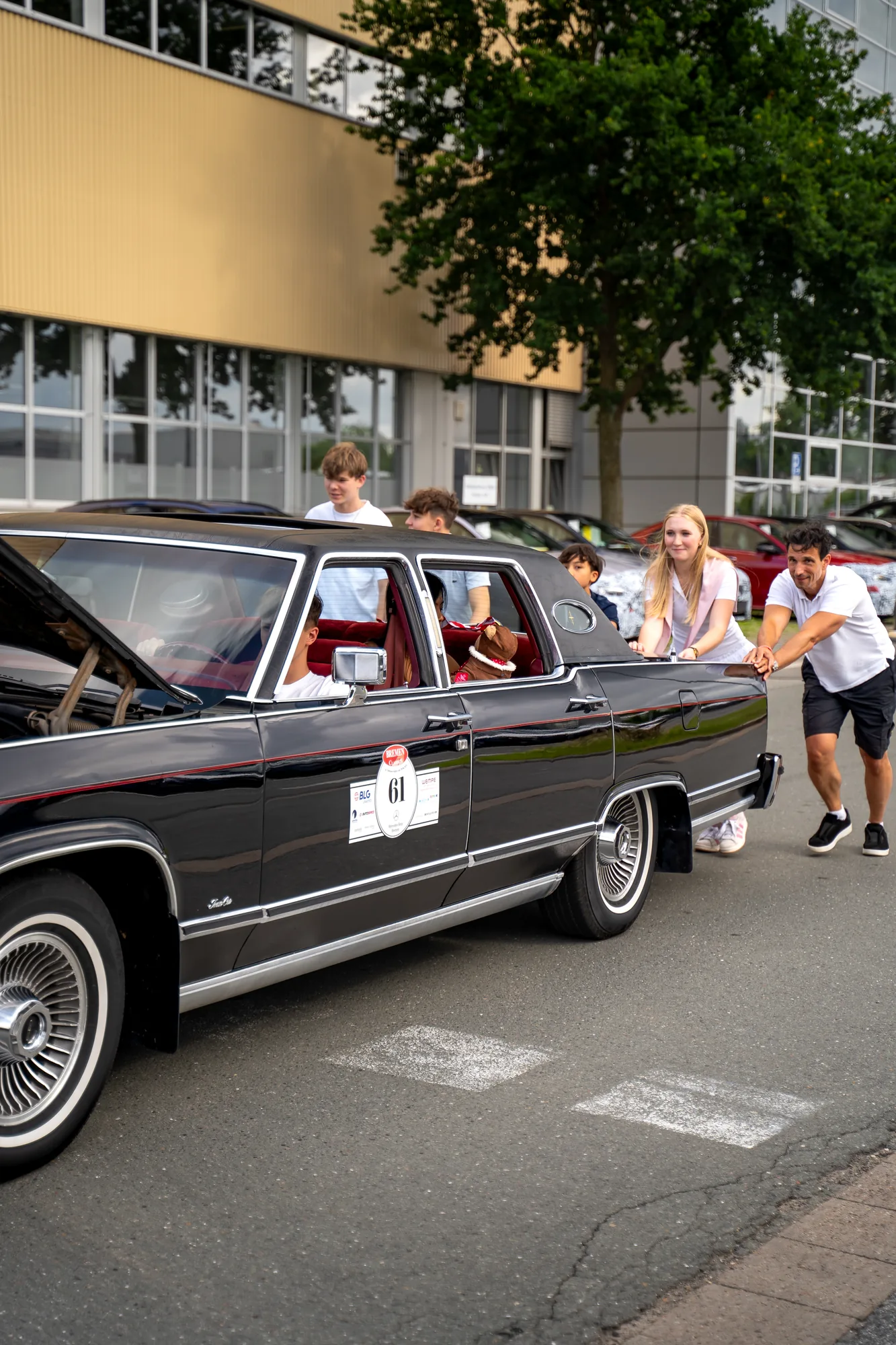 Teilnehmer schieben einen schwarzen Oldtimer bei den BOC 2025.