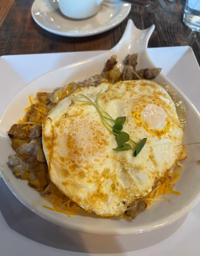 A white bowl filled with food and a fried egg.