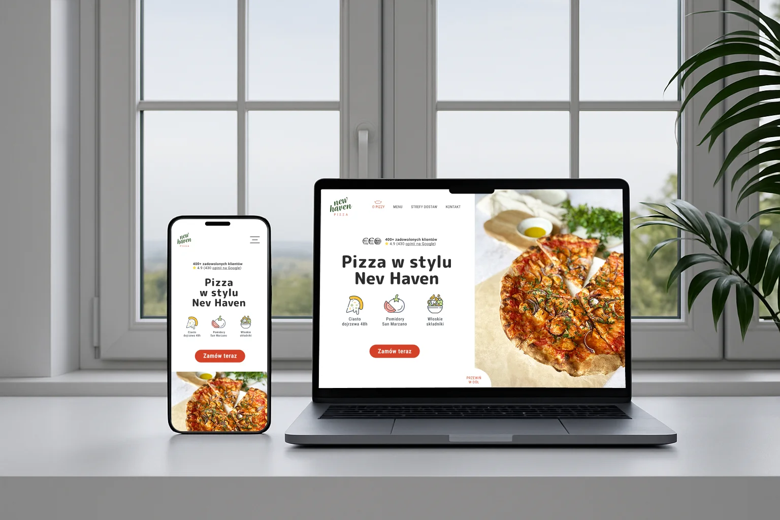 Mobile phone and laptop on a white desk displaying a pizza website in Polish, featuring a pizza image and order button.