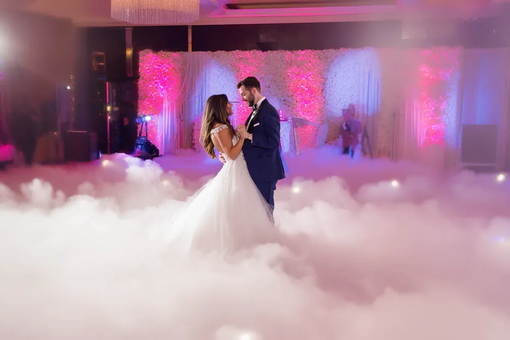 Bride and groom share a first dance surrounded by low thick fog, the dancing on clouds effect