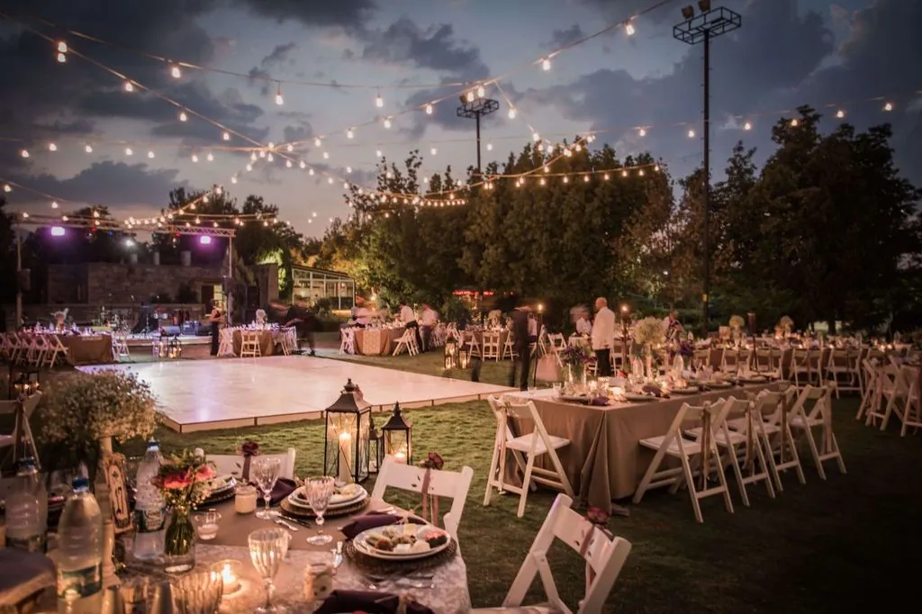 Outdoor wedding reception at dusk with string lights, a dance floor and set tables, ideal for an Orlando wedding