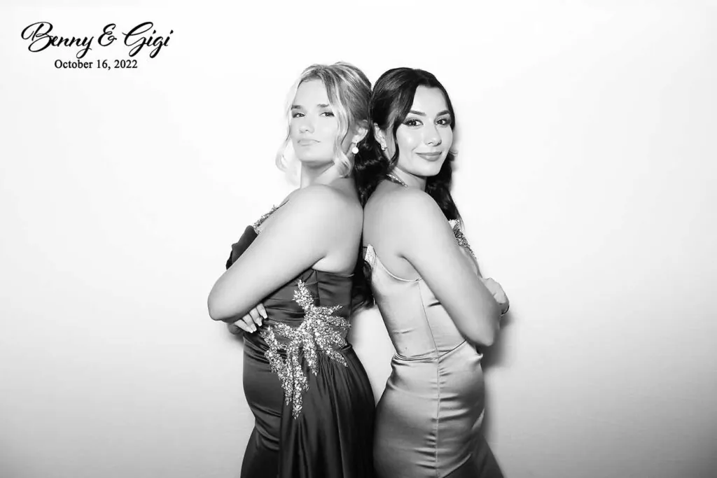 Two women in evening gowns posing back to back in a black and white glam photo booth print