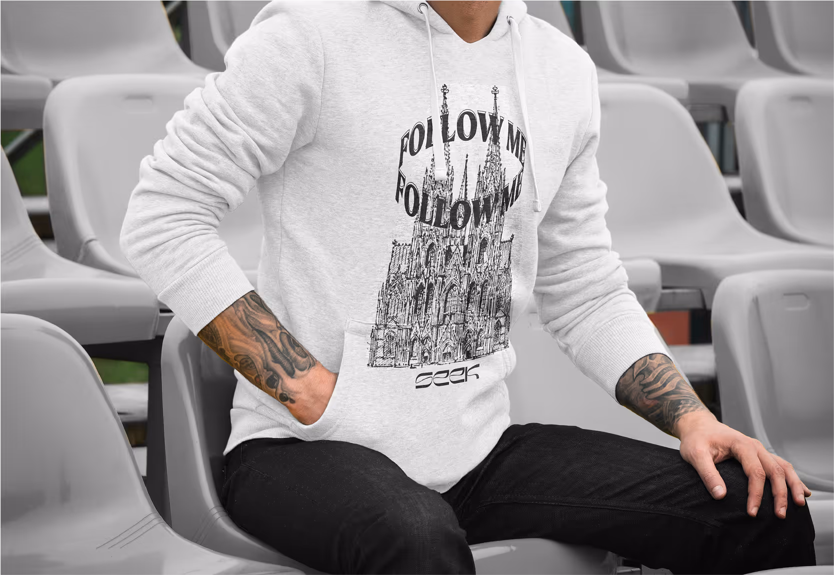 A man wearing branded merchandise sitting in bleachers.