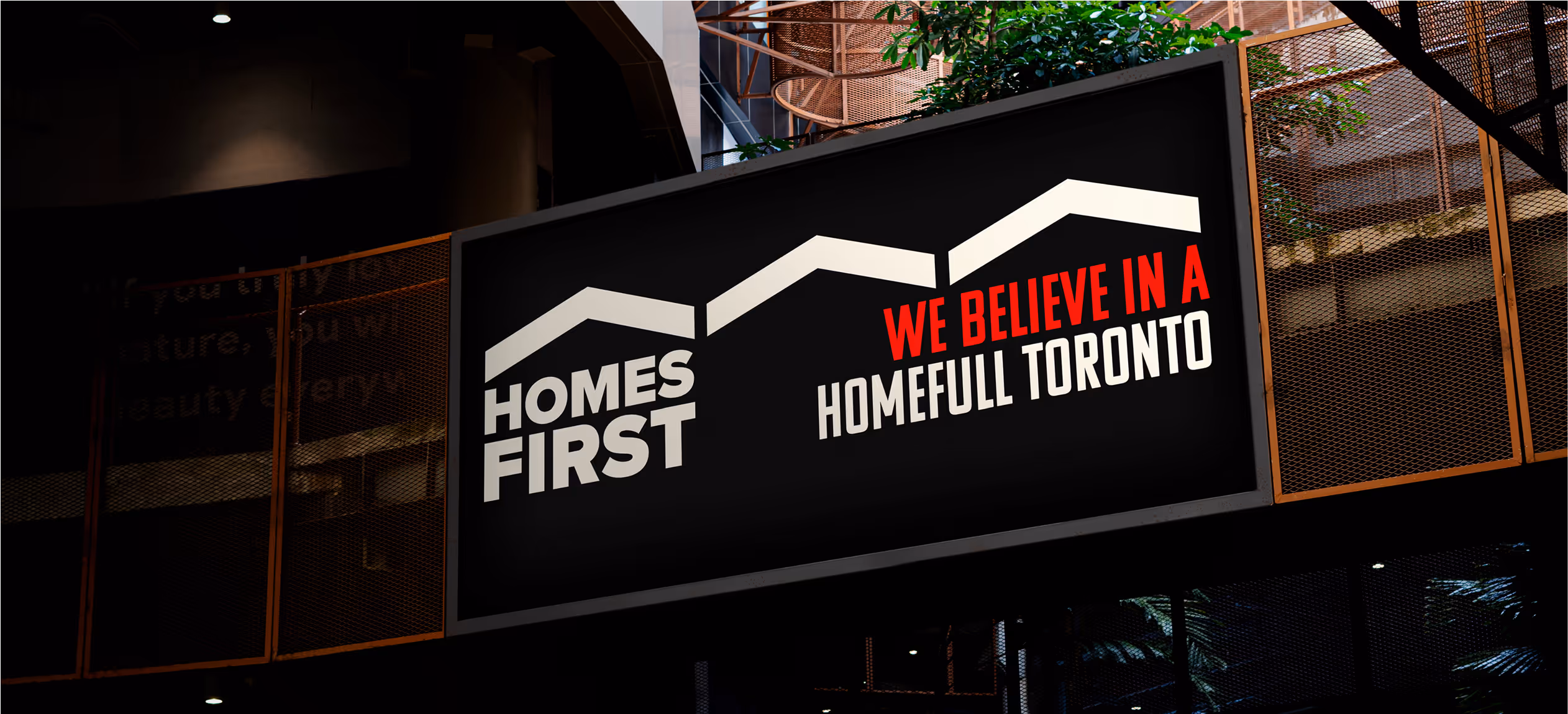 An elevated, black homes first billboard seen from below.