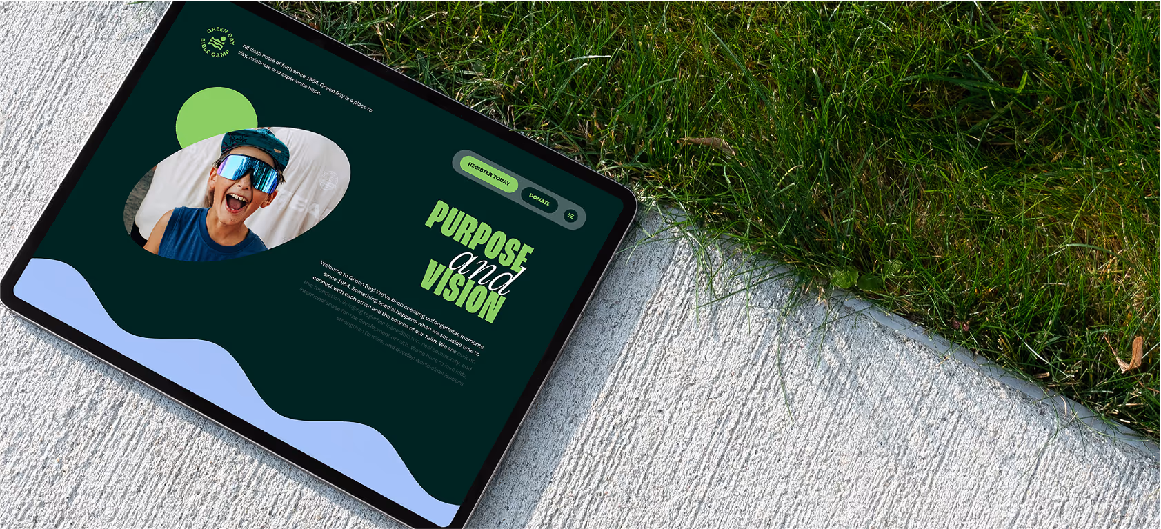 An iPad on a sidewalk showcasing the mobile website for green bay bible camp.