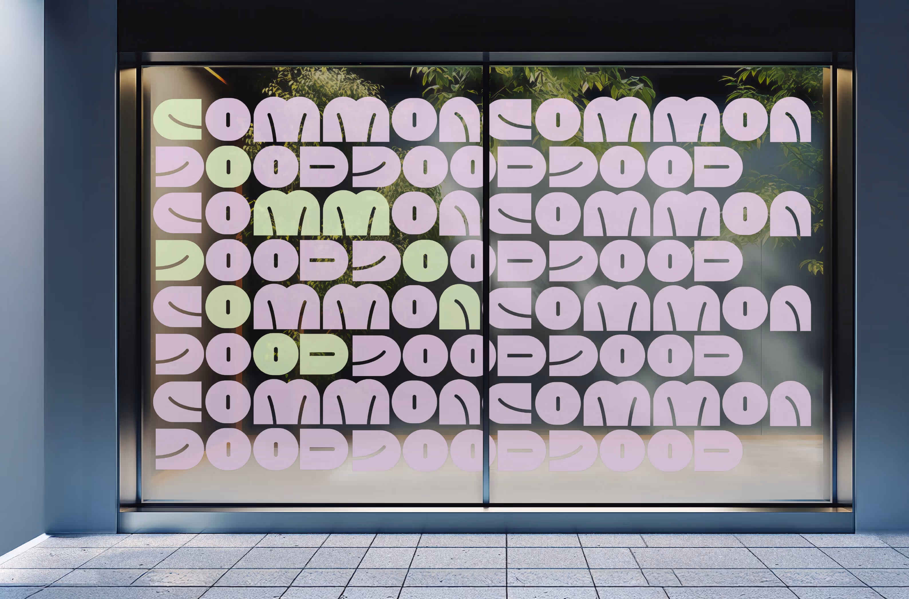 A common good branded store front decal on the window of a building. The decal has common good font cut out and repeating.